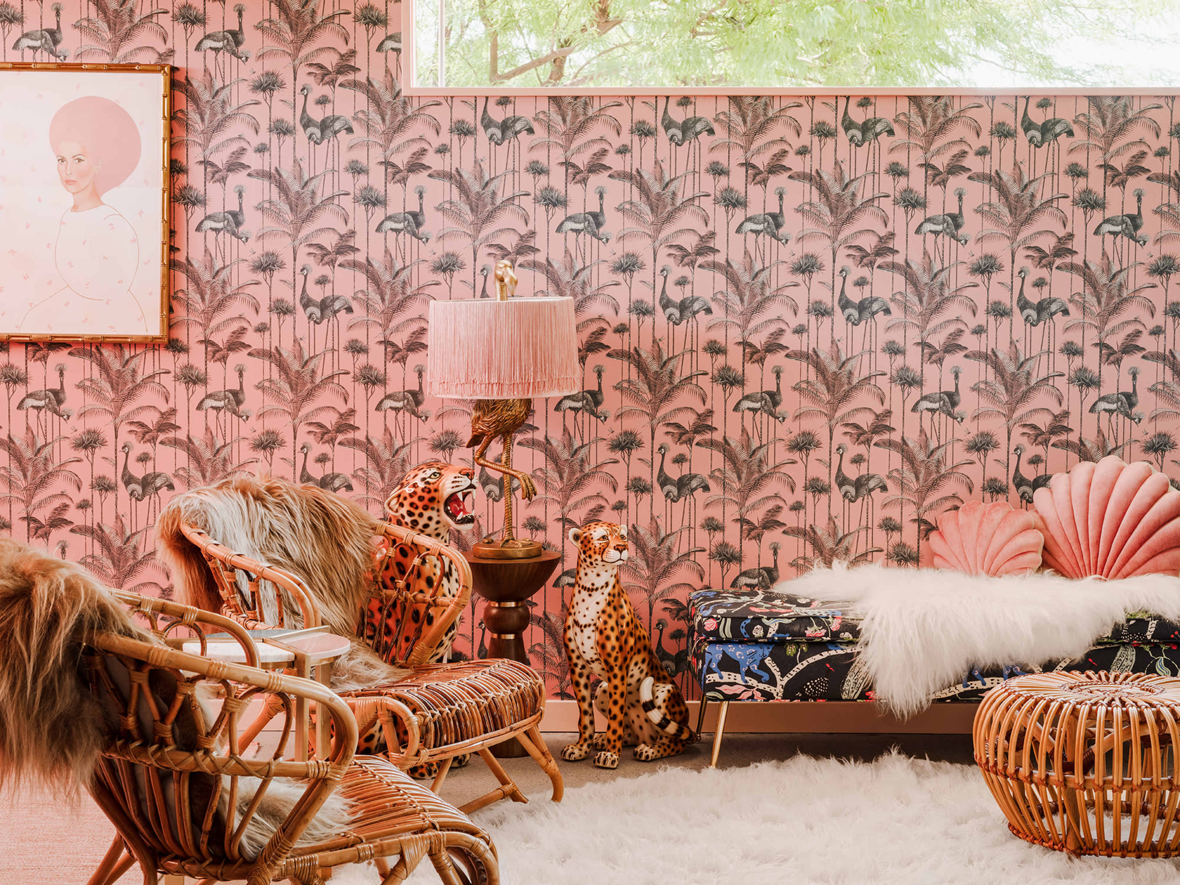 A living room with tropical-themed wallpaper, a plush white rug, a lamp with a bird design, and various animal statues, along with wicker furniture.