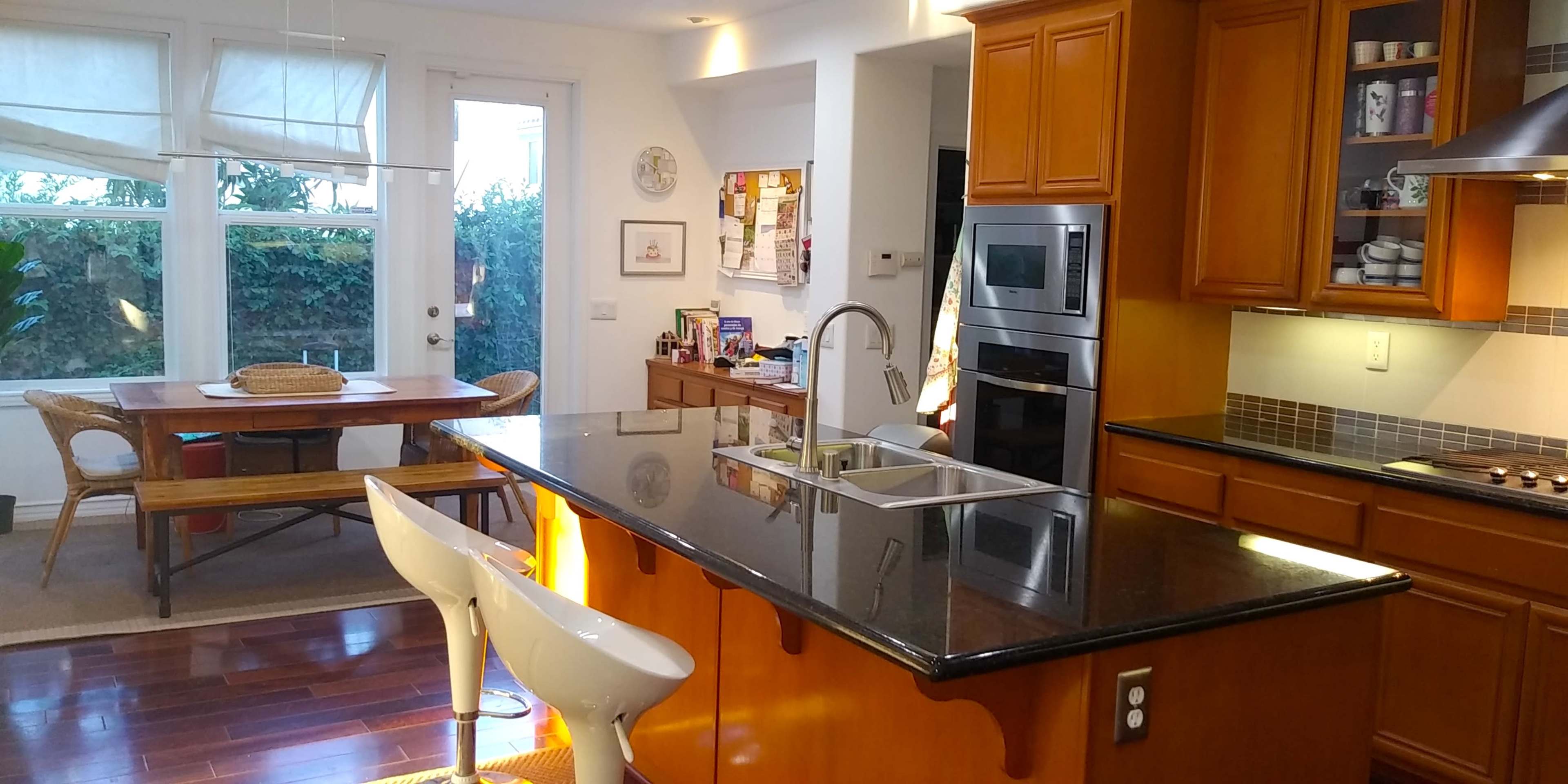 A modern kitchen with a large island, stainless steel appliances, and a dining area with a table and chairs.