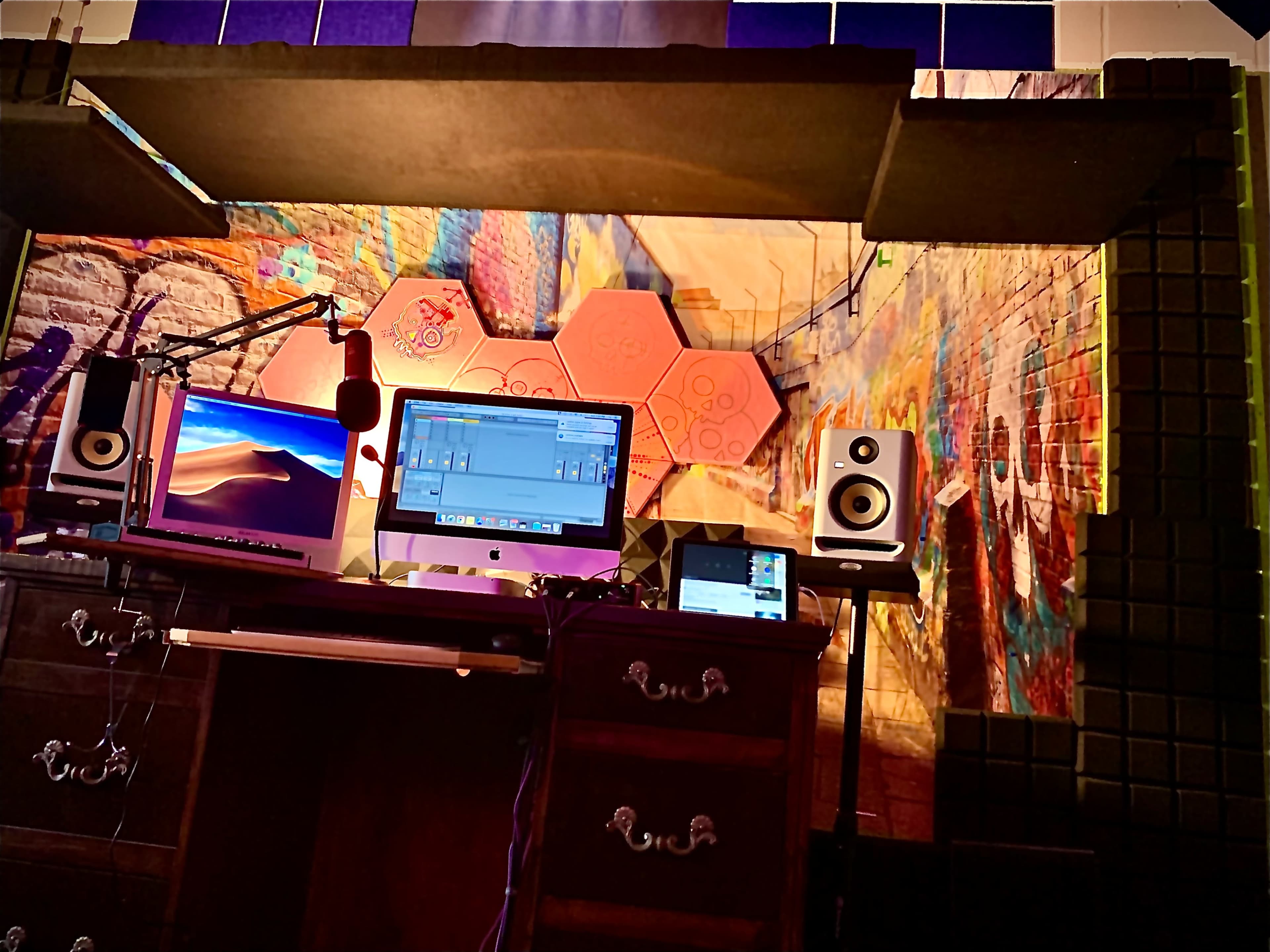 A workstation with a computer, audio speakers, and a microphone set against a colorful, graffiti-style backdrop.