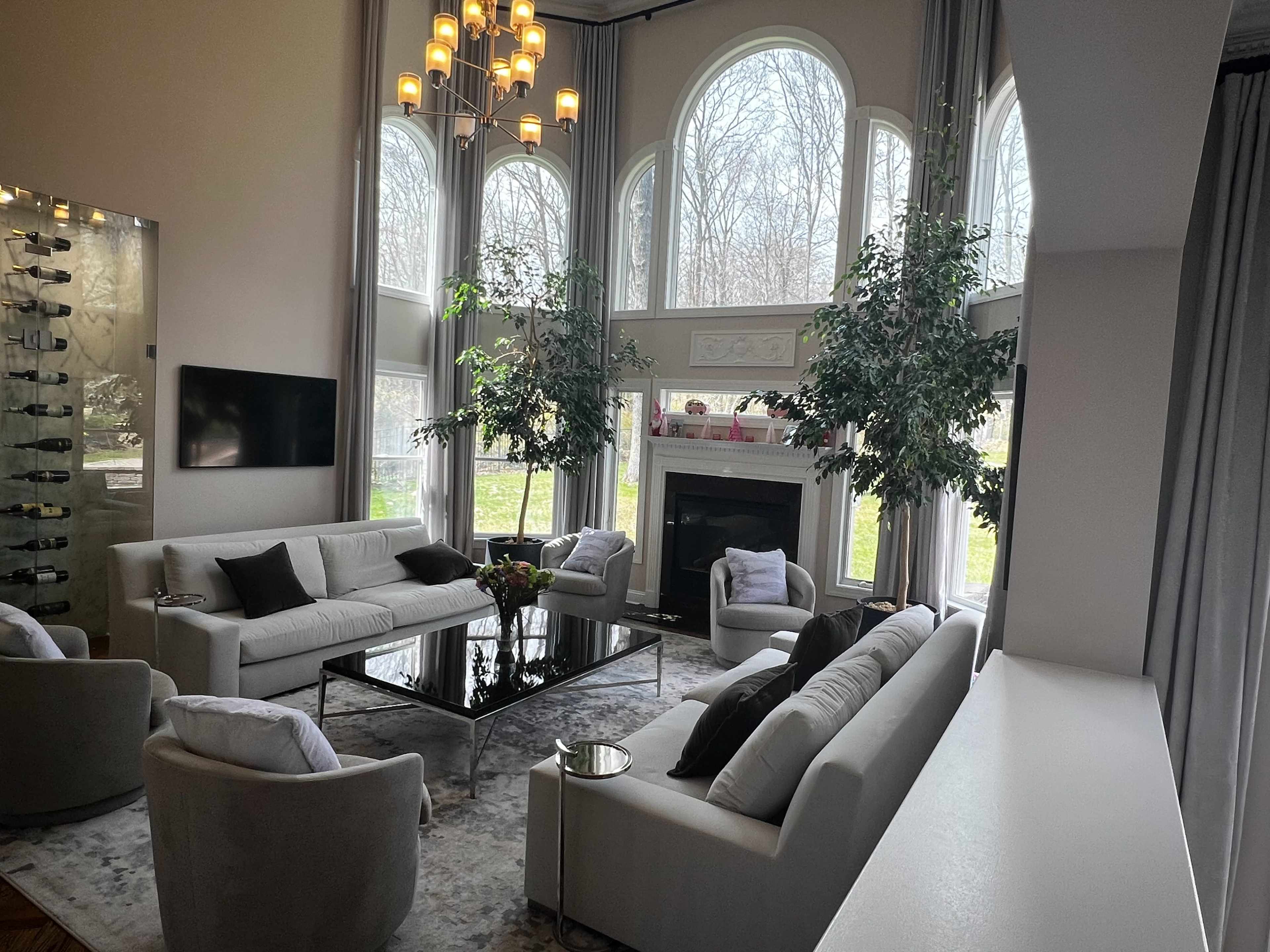 The living room features large windows, a modern seating arrangement, a glass coffee table, and a fireplace.
