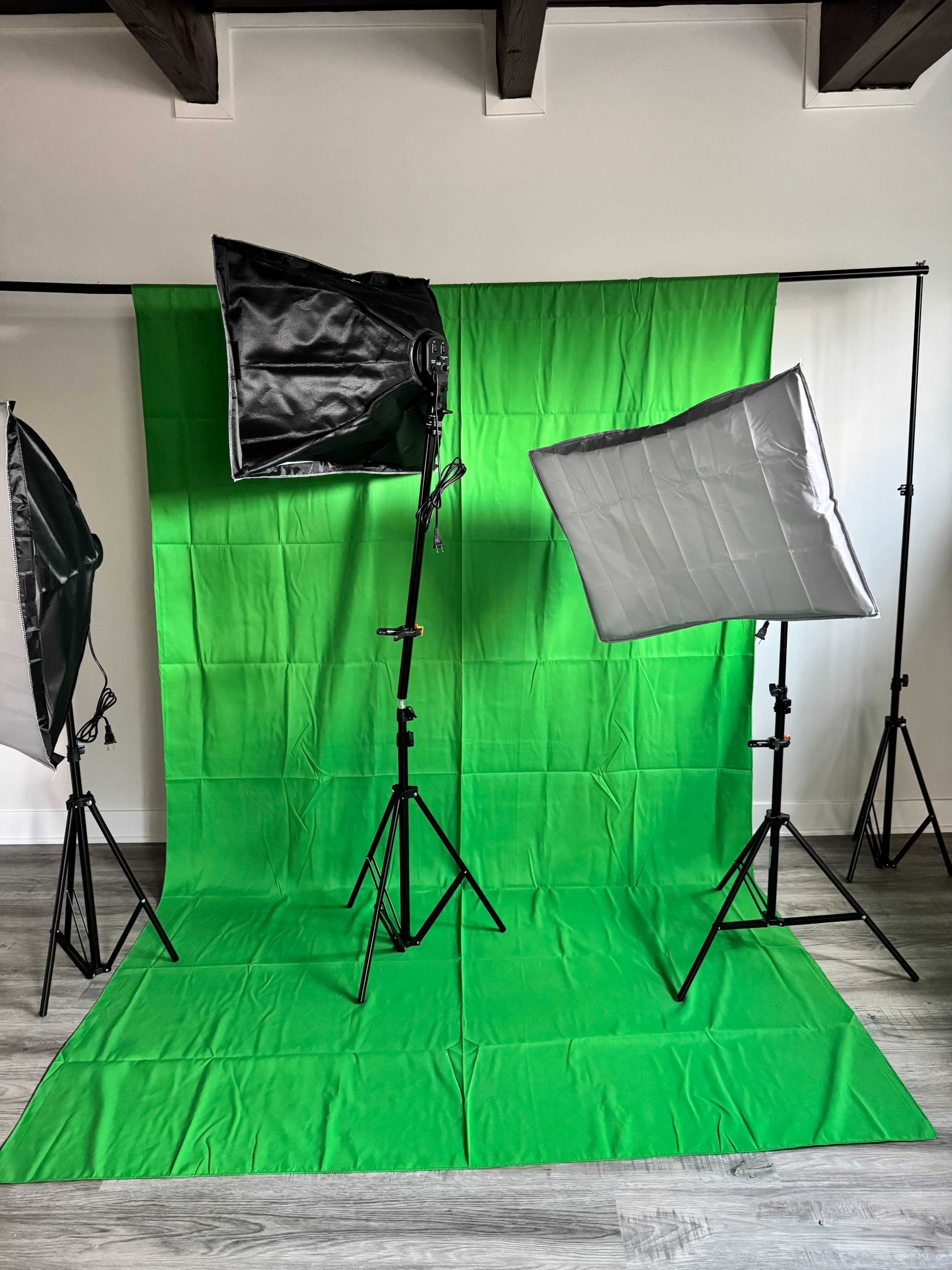 The image shows a photography setup featuring a green backdrop with two lighting softboxes on stands.