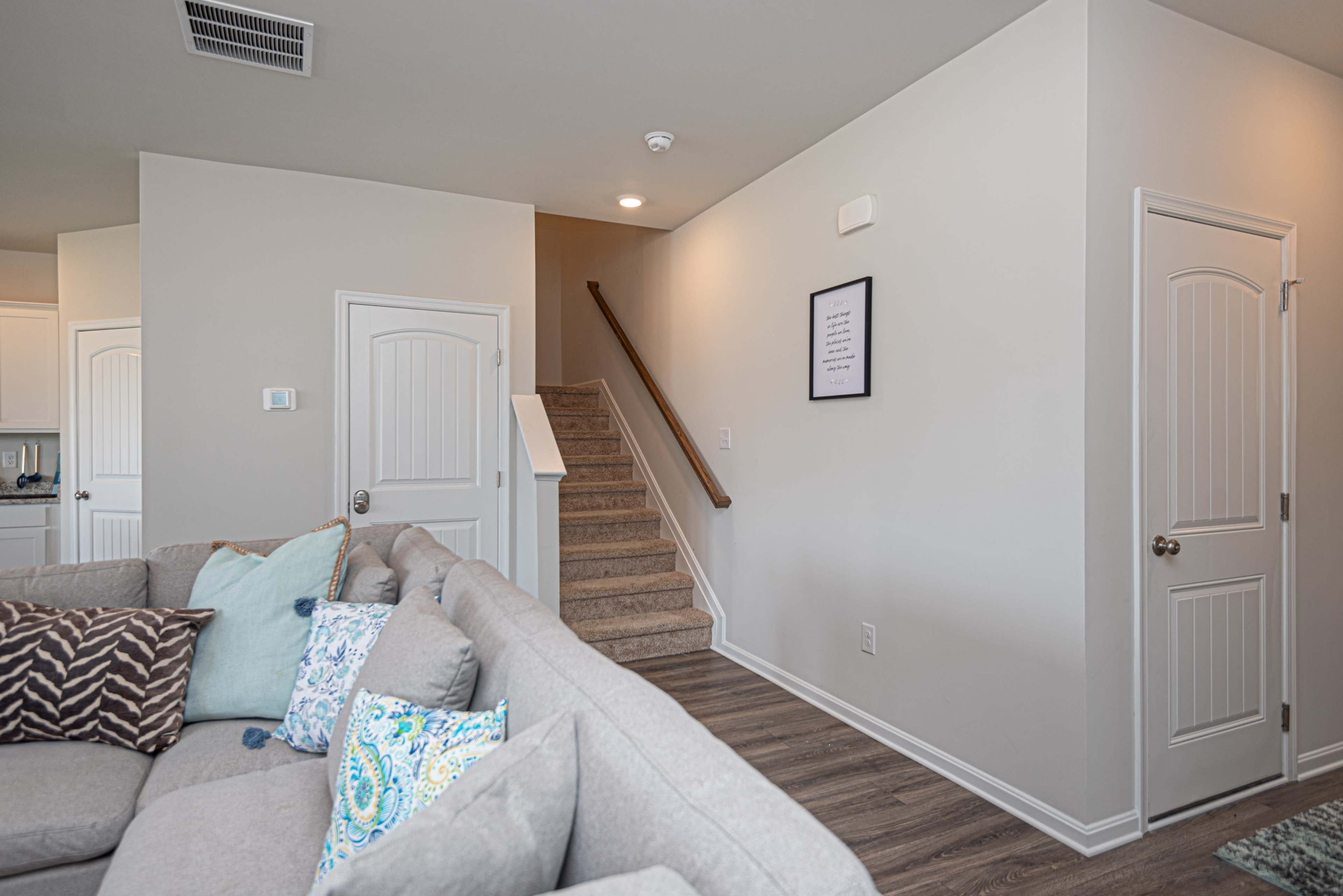 A living room with a sectional sofa facing a staircase leading to an upper level.
