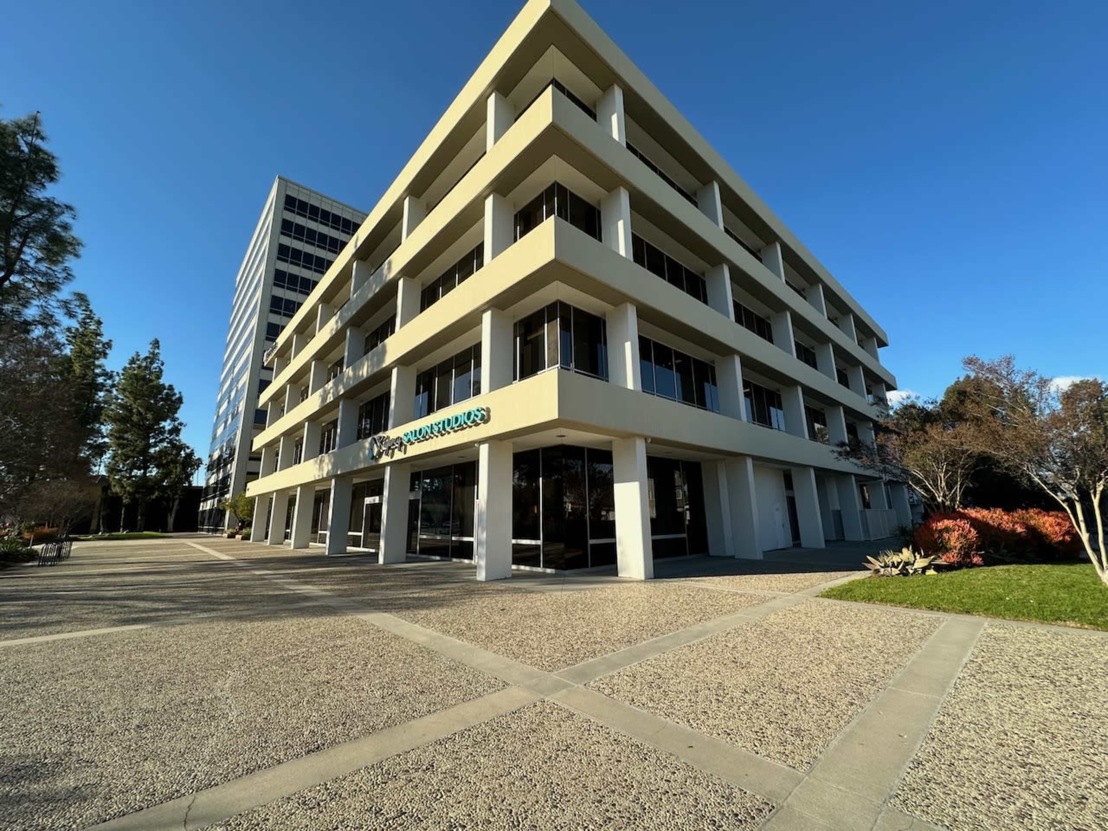 A modern, multi-story office building with a glass front and landscaped surroundings.