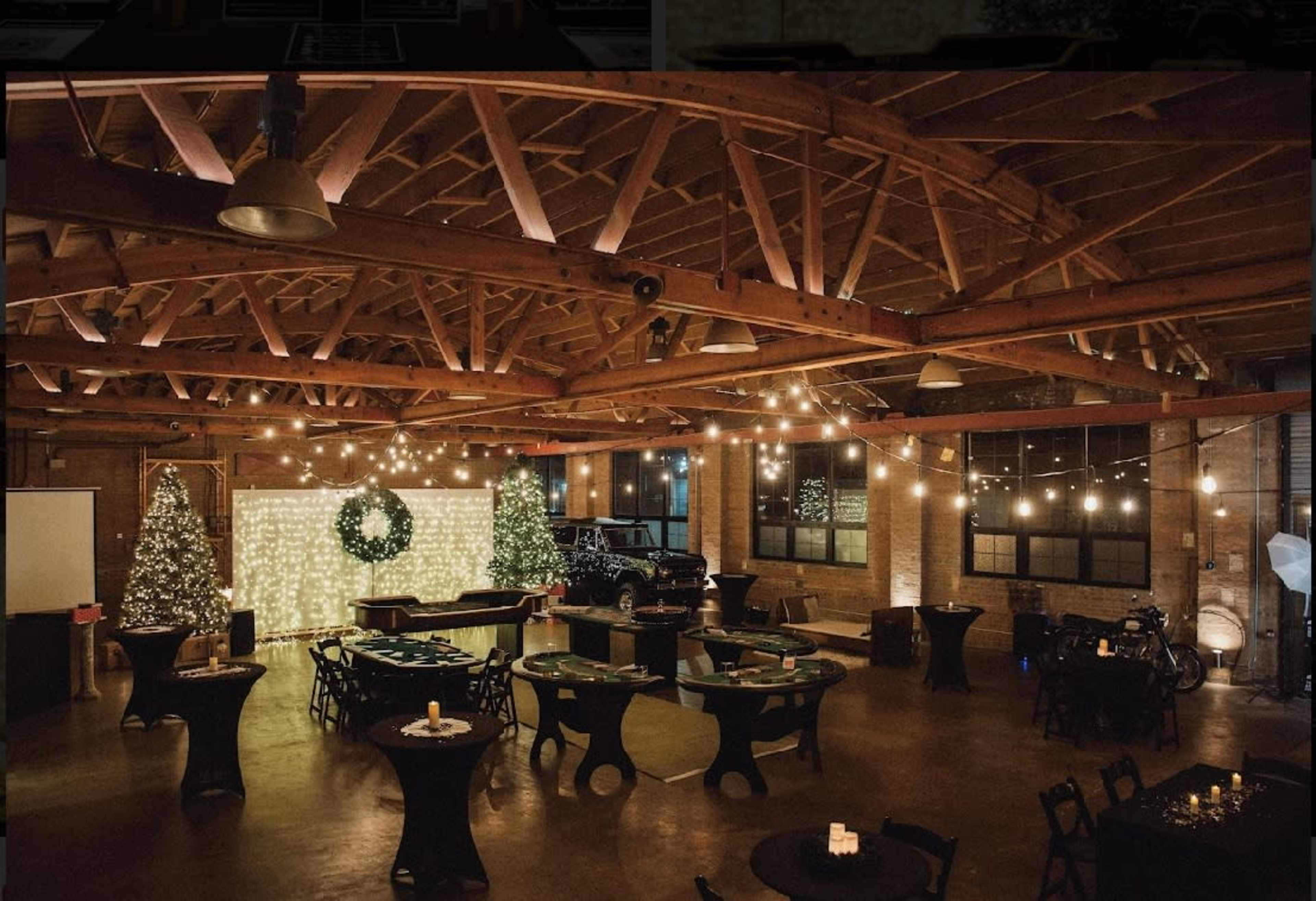 The spacious venue features tables and chairs arranged around a central area adorned with festive decorations, including Christmas trees and string lights.