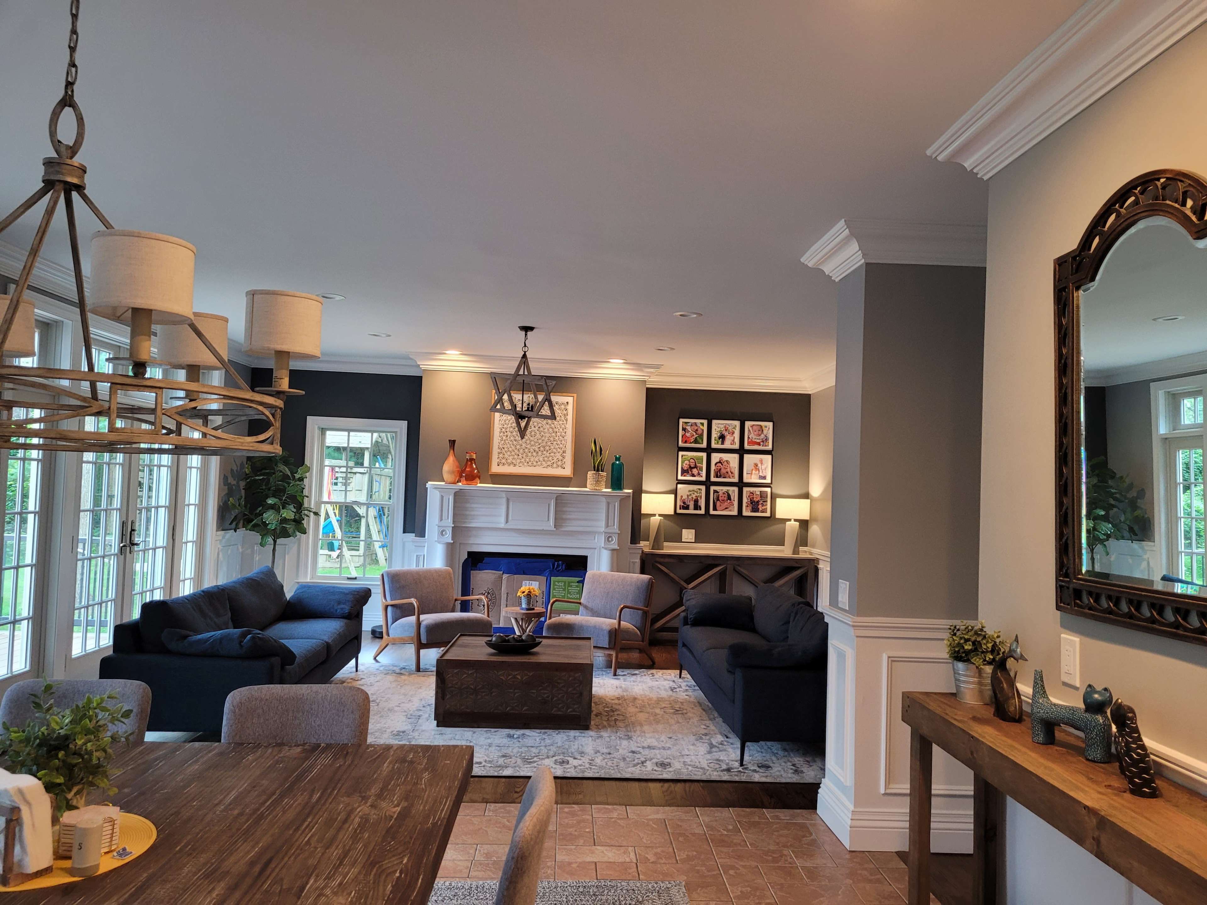 A modern living room featuring a fireplace, framed artwork on the walls, and a dining area with a wooden table and chairs.