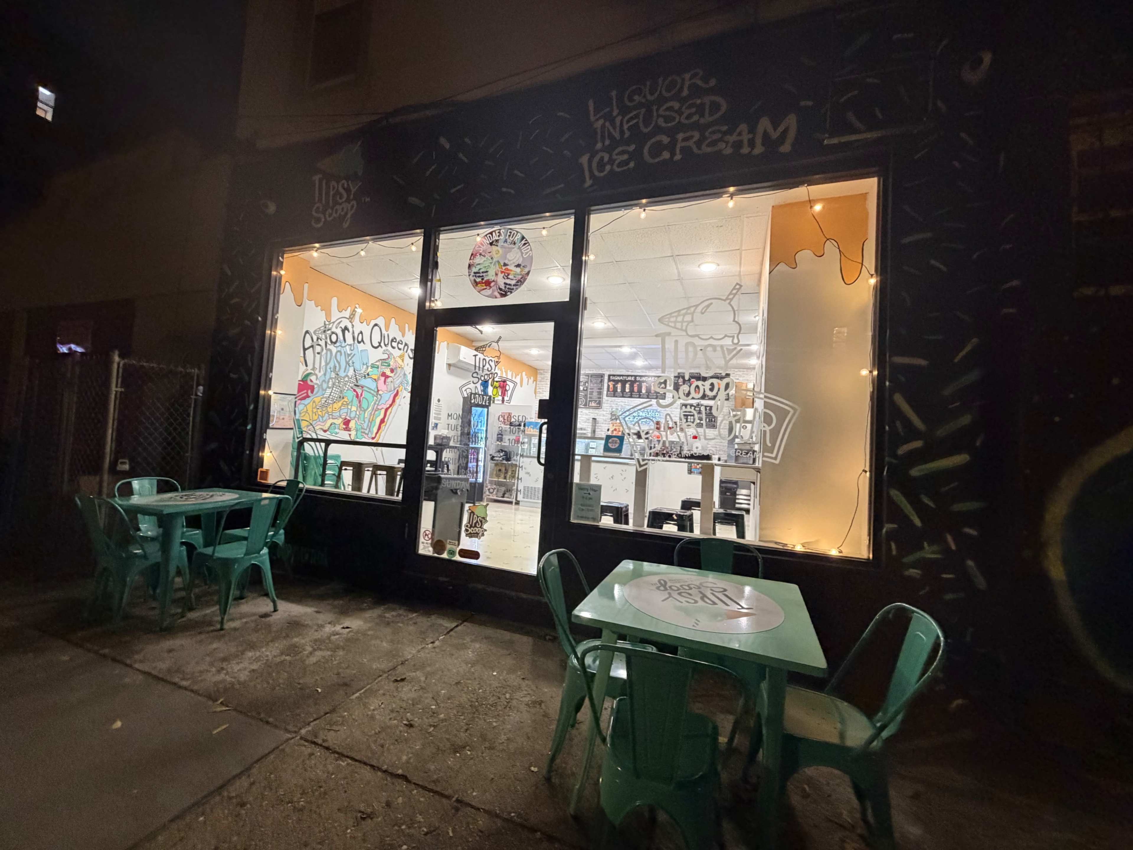 The image shows a brightly lit ice cream shop with liquor-infused offerings, featuring outdoor seating and colorful wall art.
