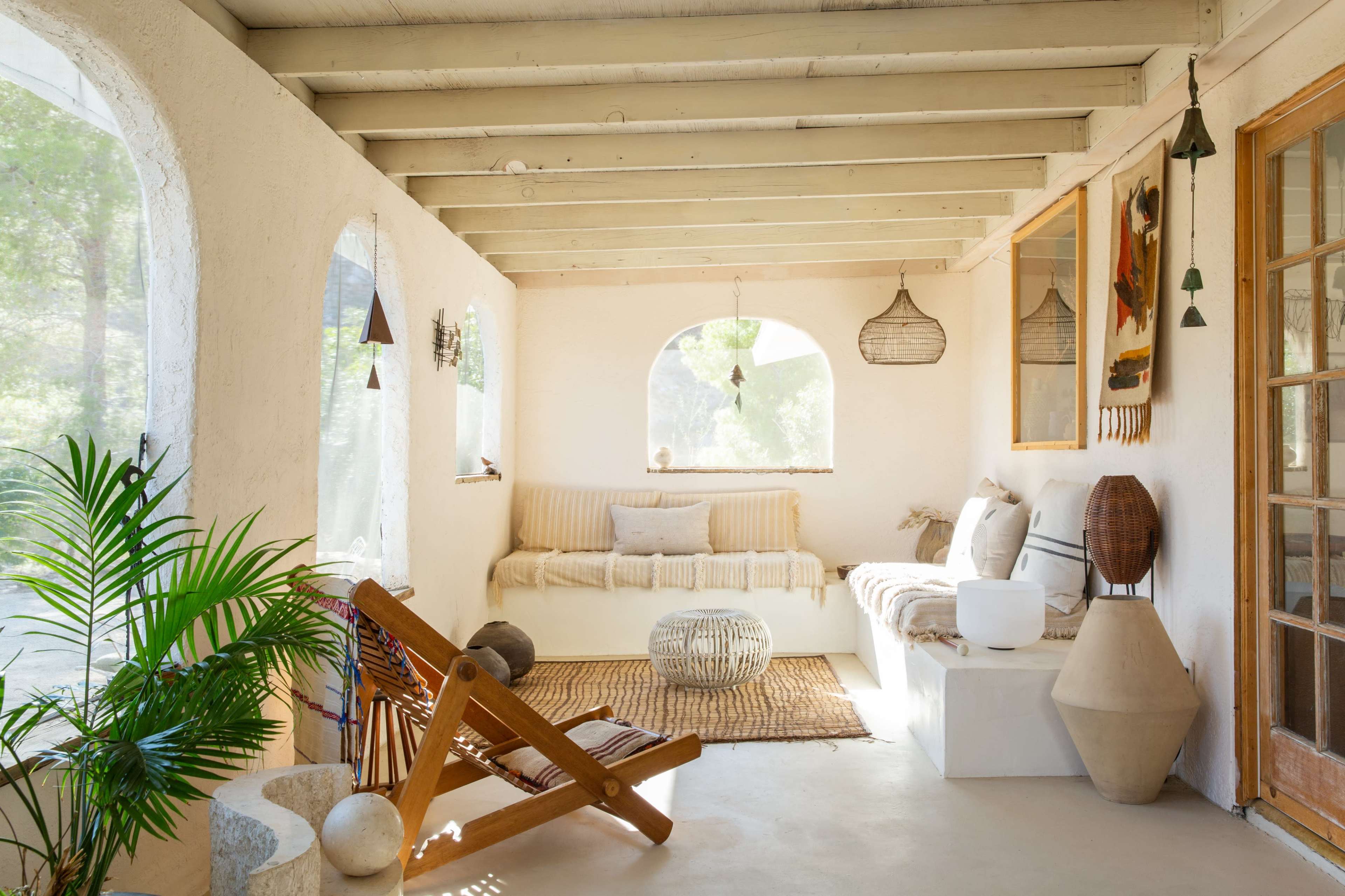 A sunlit, airy room with arched windows, a seating area with a sofa and decorative elements, and a mix of natural textures and materials.