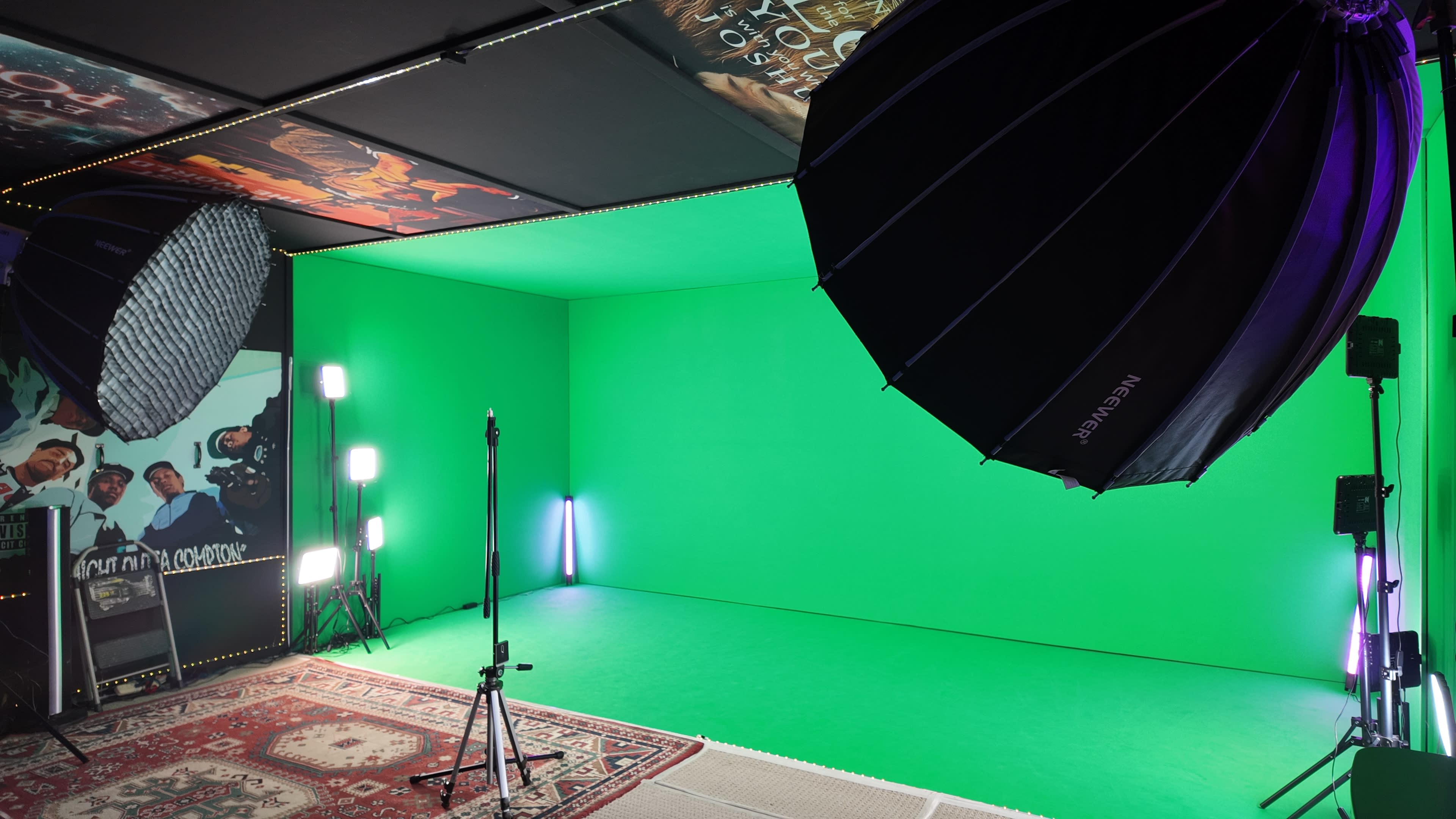The image depicts a green screen studio featuring lighting equipment and a patterned rug on the floor.