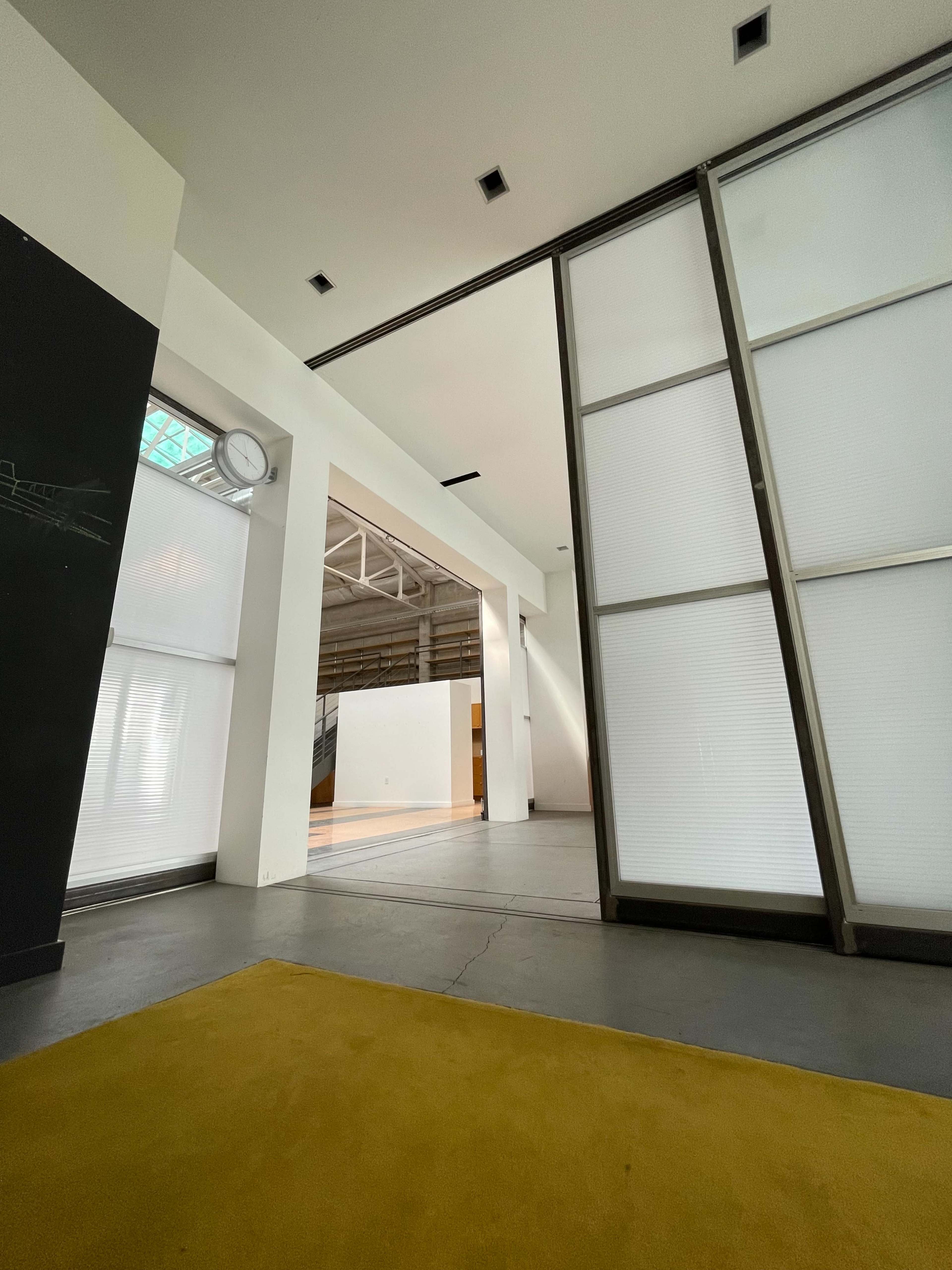 The interior of a modern building with large windows and a yellow area rug on the floor.