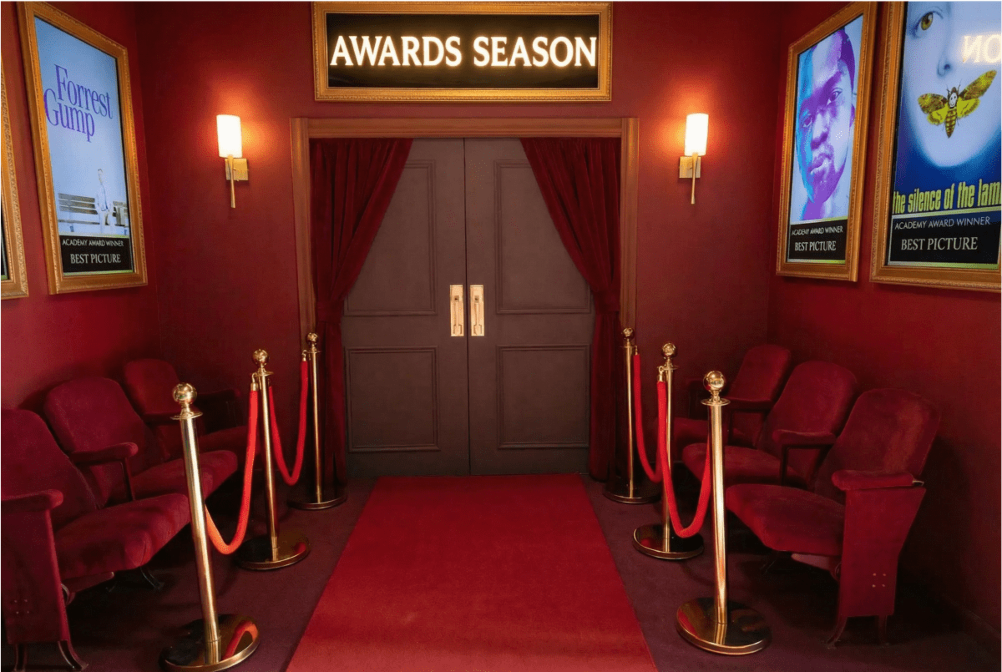 The image shows an elegant hallway decorated with red velvet seats, red ropes, and gold stanchions, leading to a double door labeled “AWARDS SEASON” with framed movie posters on the walls.