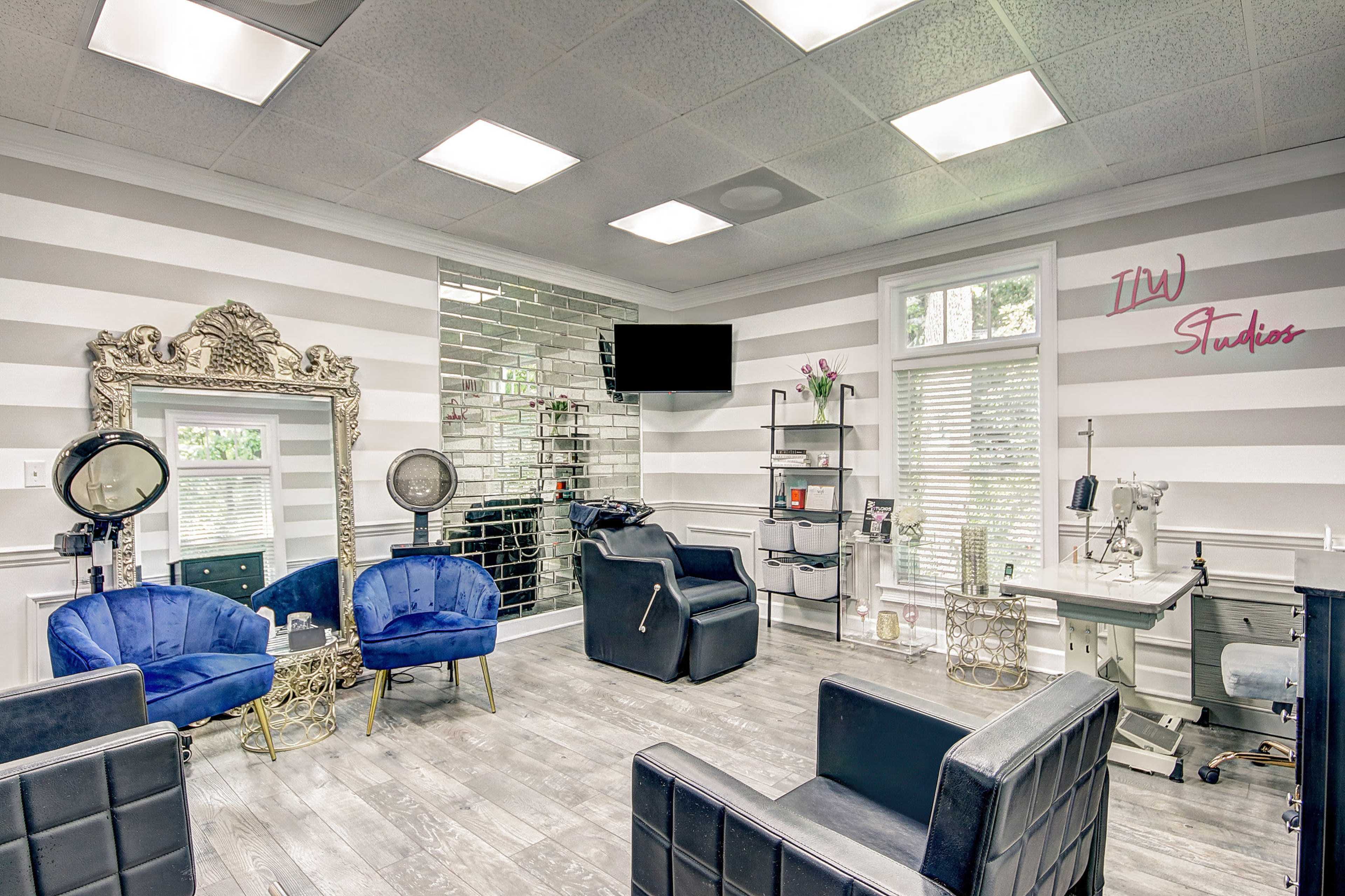 A stylish hair salon with blue chairs, a mirrored wall, and various styling stations.