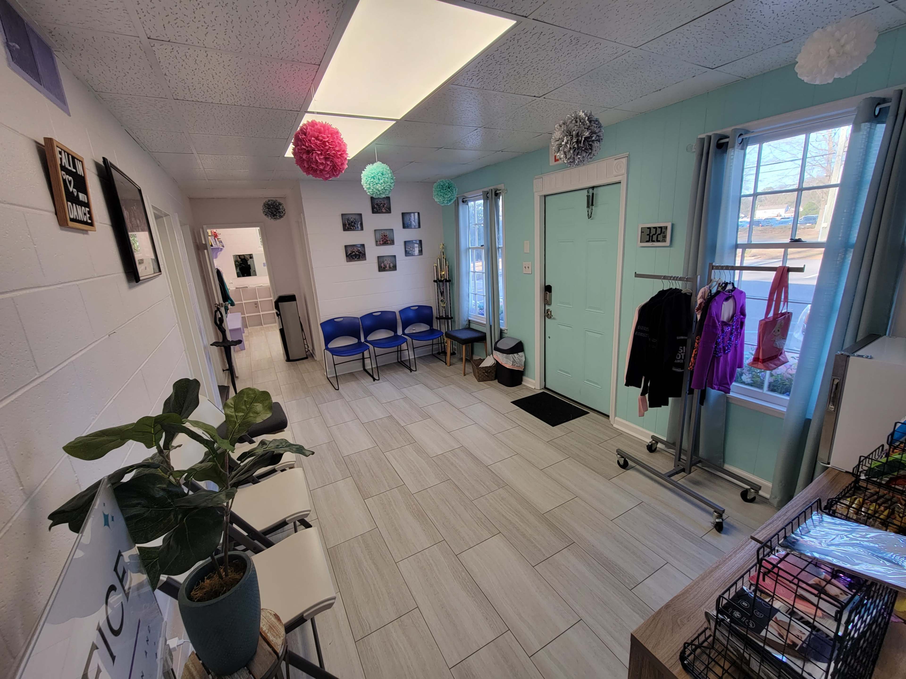 A waiting area with blue chairs, a door with a light turquoise finish, and decor including photos and paper pom-poms hanging from the ceiling.