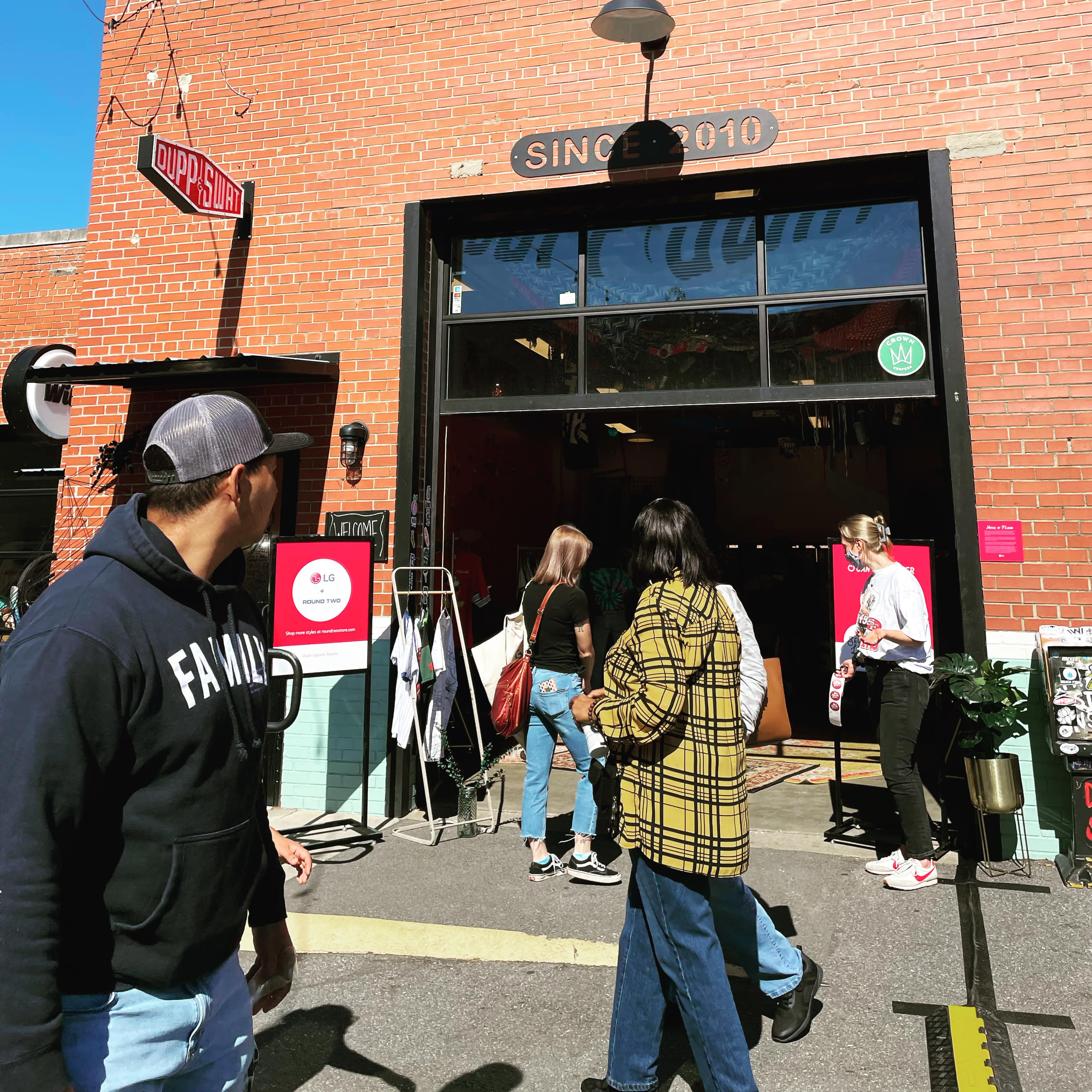 A group of people walks past a storefront with a sign reading "Since 2010."