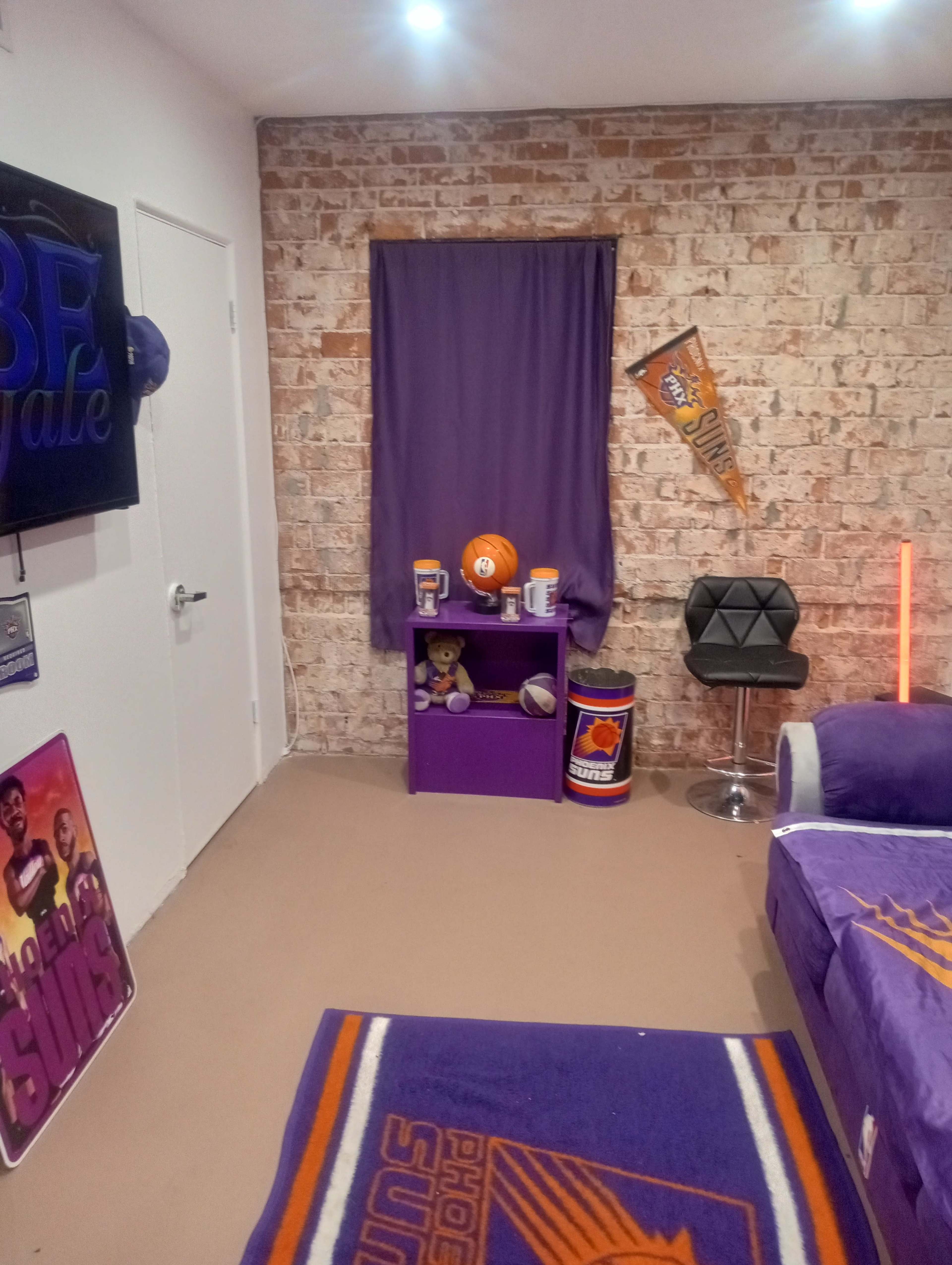 The image shows a decorated room featuring purple walls, sports memorabilia, and a basketball-themed theme centered around a basketball team.