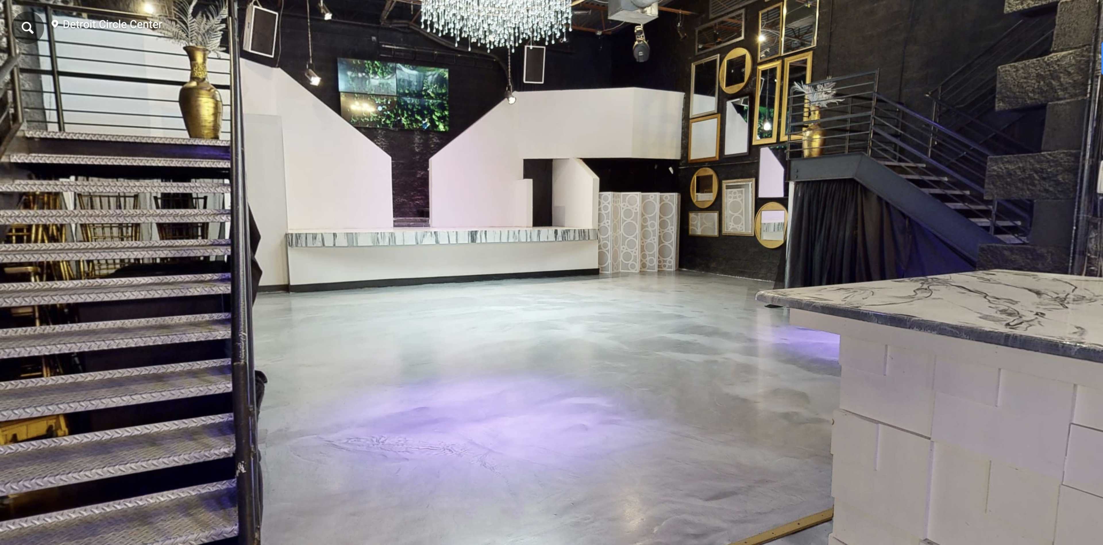 A spacious event venue with a polished concrete floor, a bar area, and decorative mirrors on the walls.