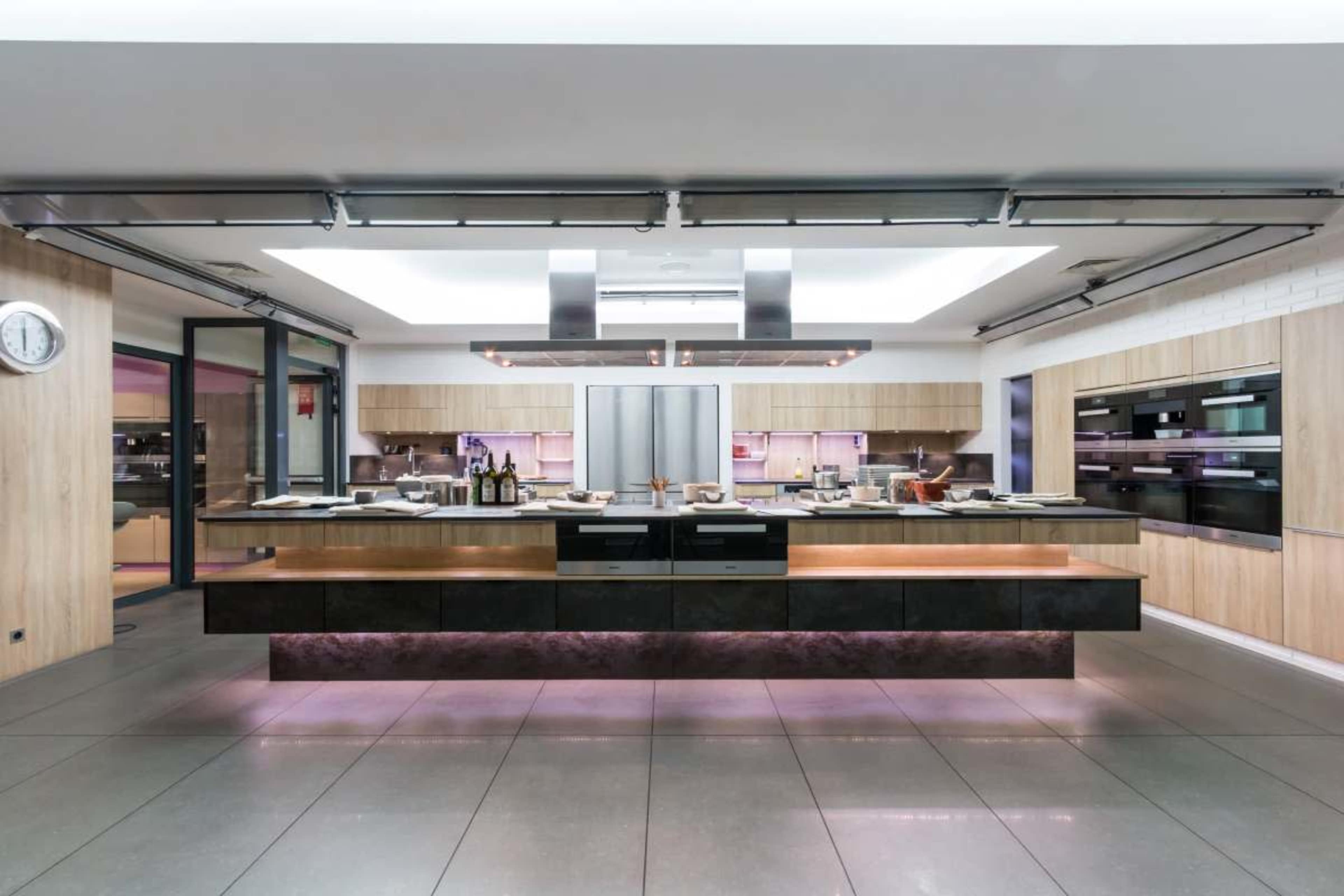 A modern kitchen features a large central island with a sleek design, stainless steel appliances, and ambient lighting.