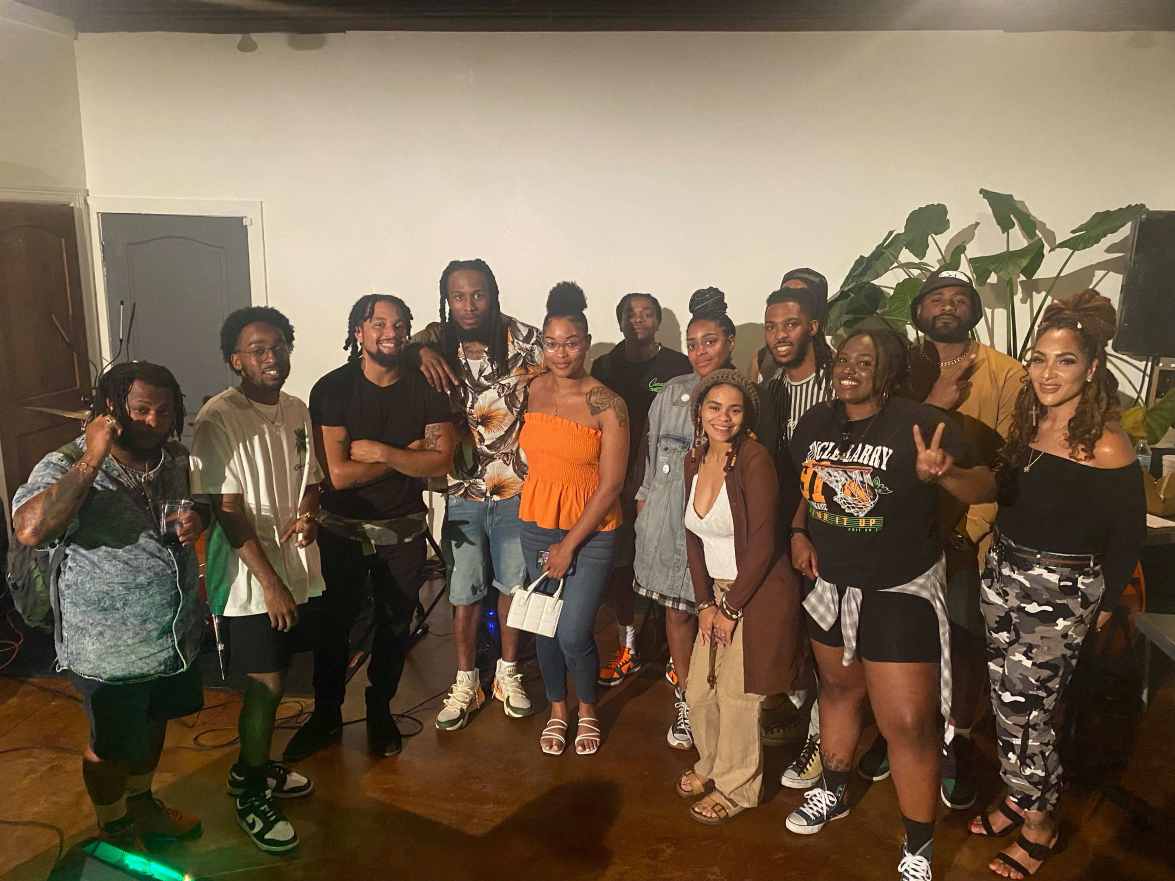 A group of diverse individuals poses together in a well-lit indoor space with plants in the background.