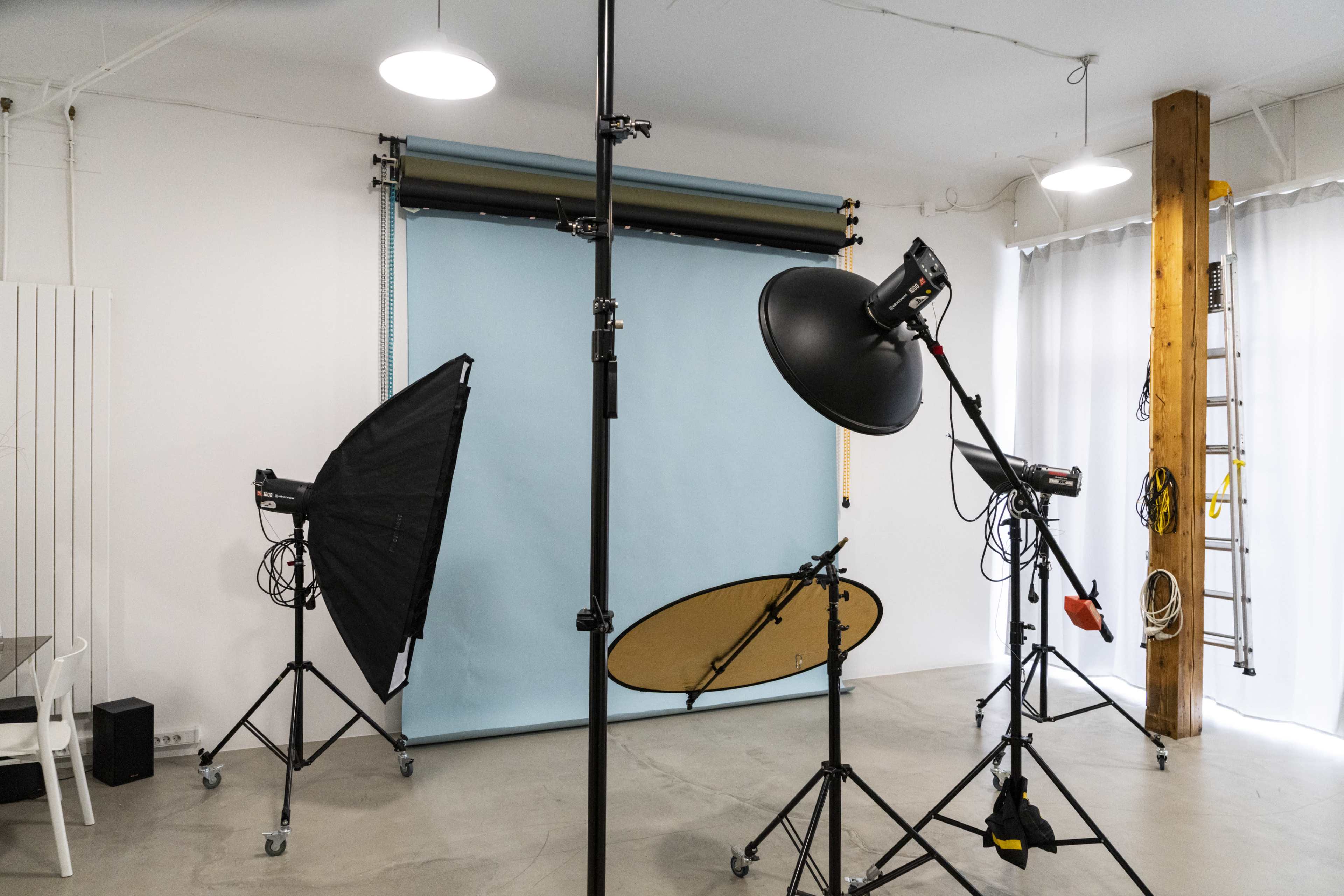 The image shows a photography studio equipped with lighting equipment, a backdrop, and various tools for taking pictures.