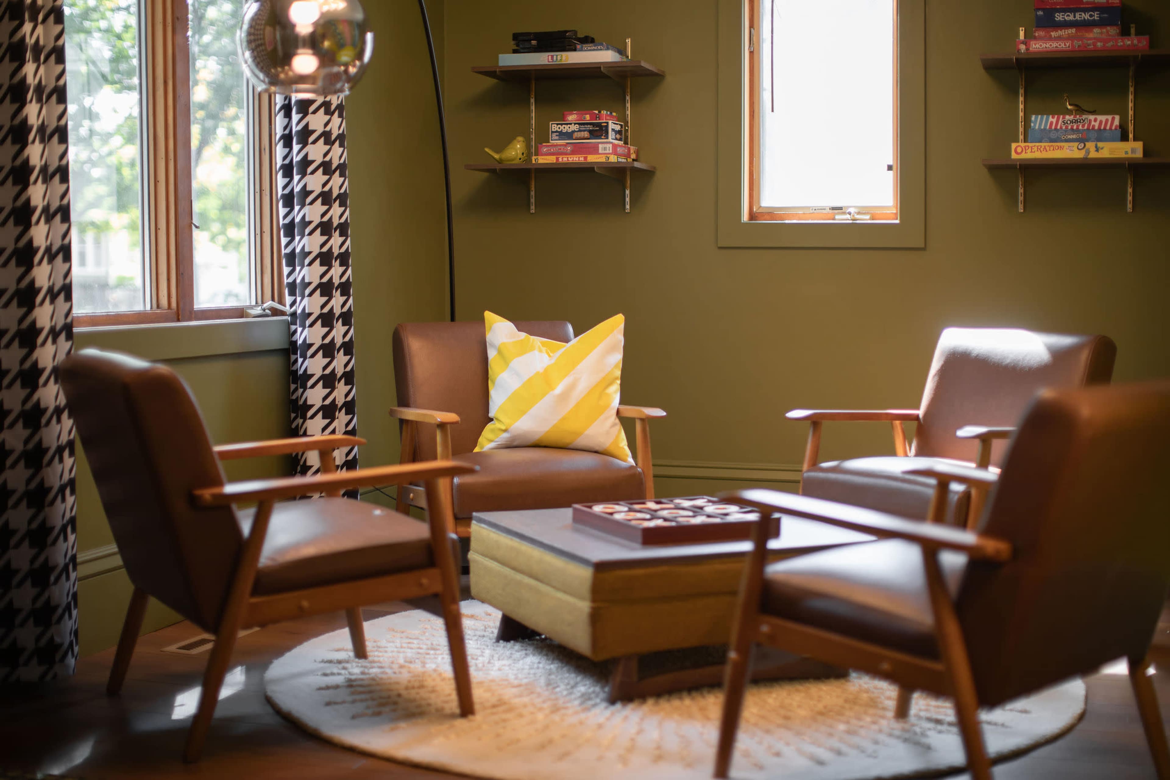 A cozy sitting area with four upholstered chairs arranged around a low table on a circular rug, set against a green wall.