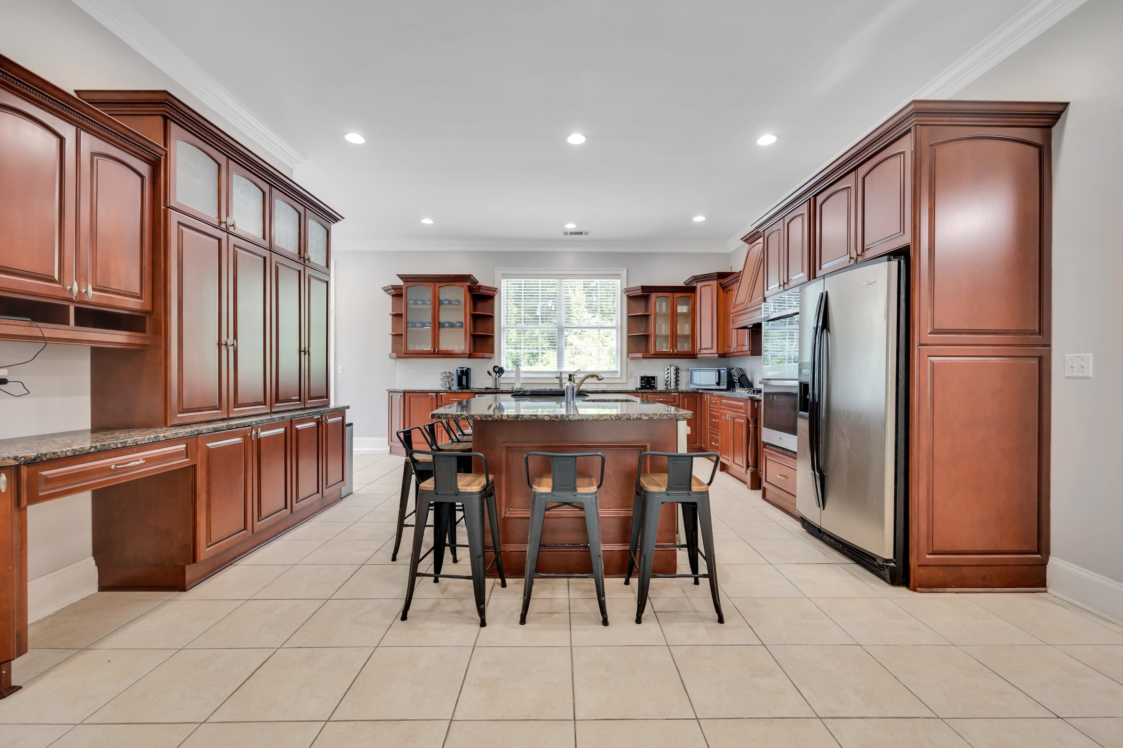 A kitchen with wooden cabinetry, a central island with seating, and stainless steel appliances.