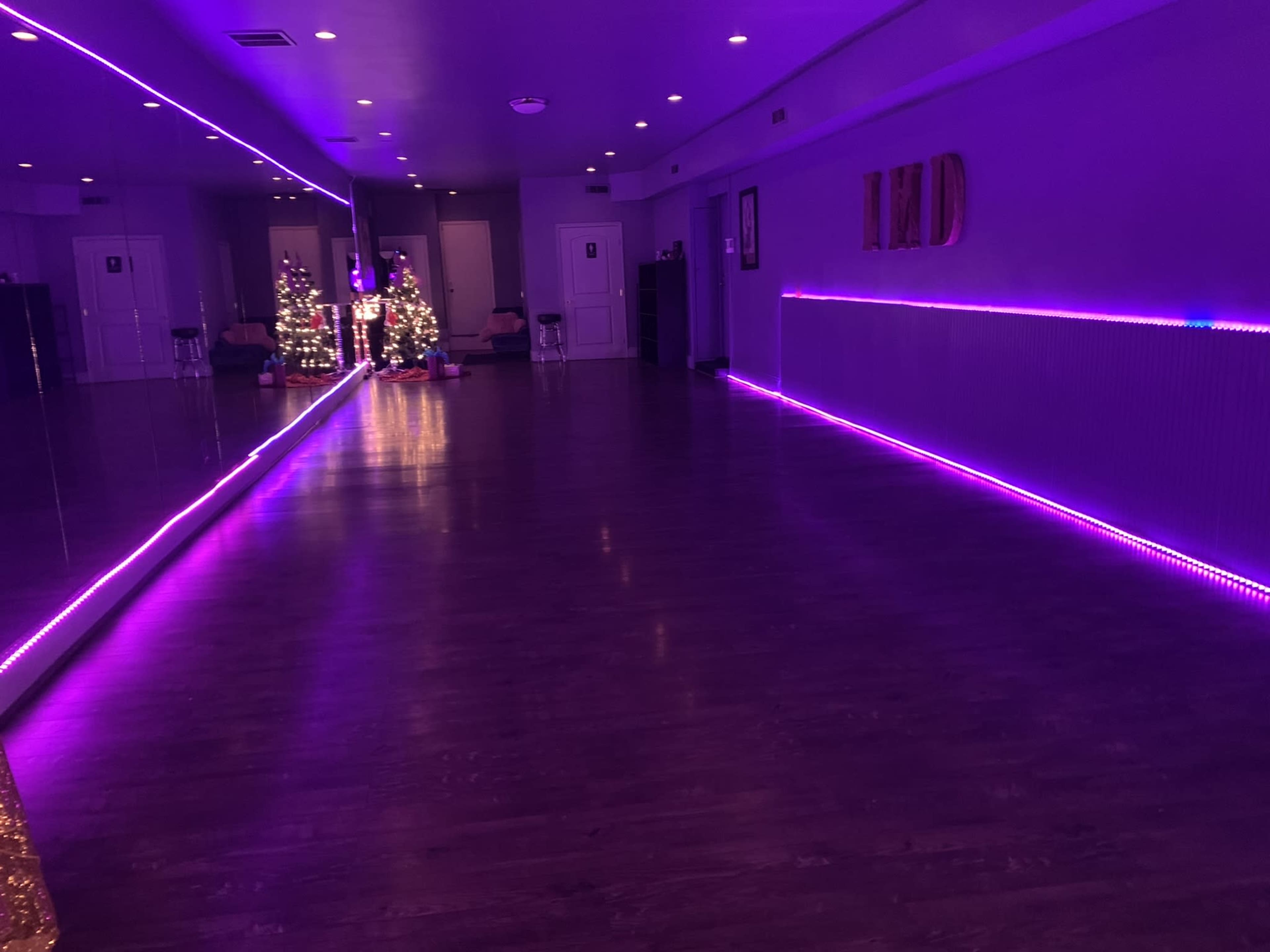A dance studio with purple LED lighting, a large mirror, and a decorated Christmas tree in the corner.