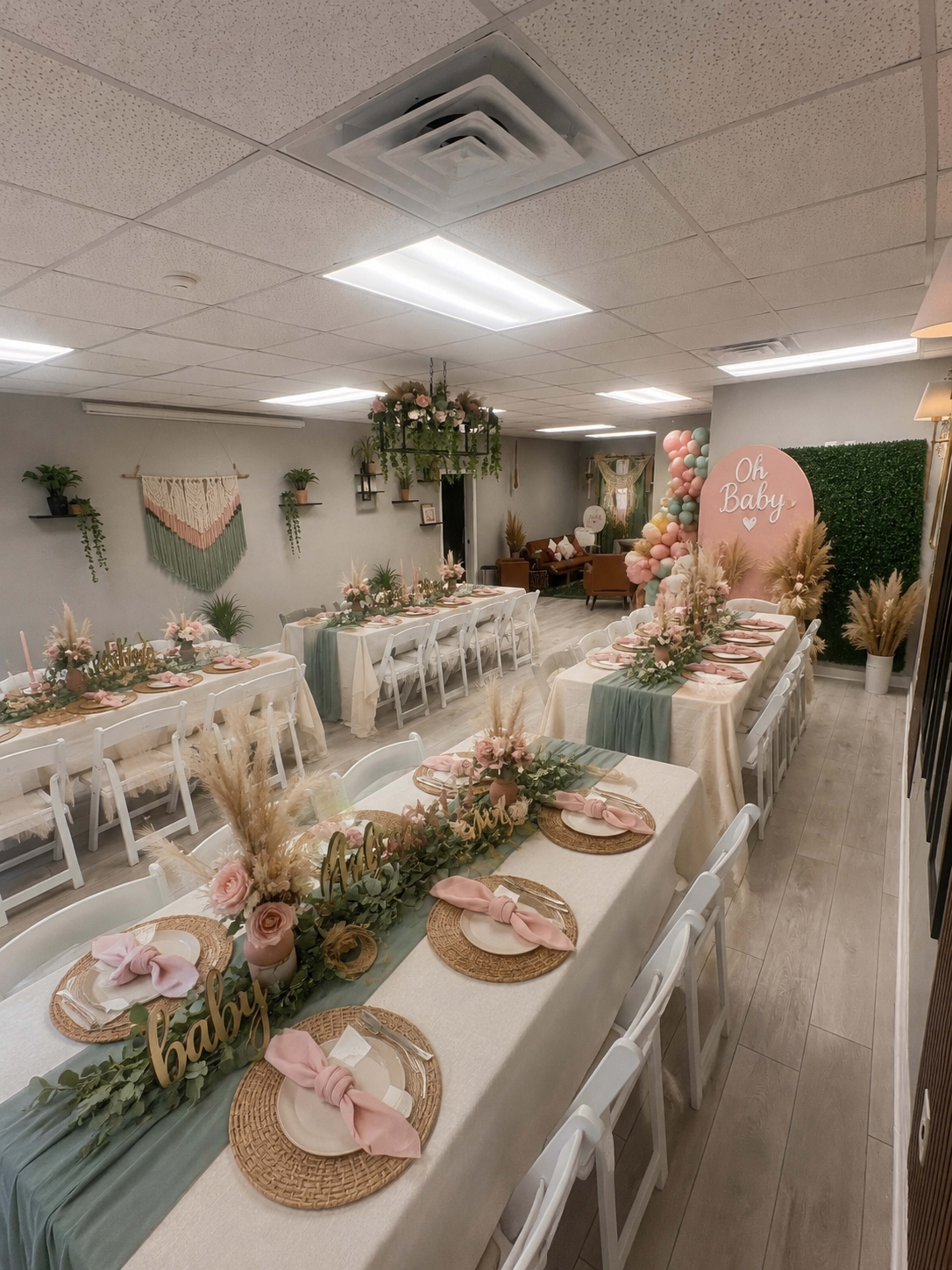 The image shows a decorated room set up for a baby shower, featuring tables adorned with floral centerpieces, table runners, and balloons in the background.