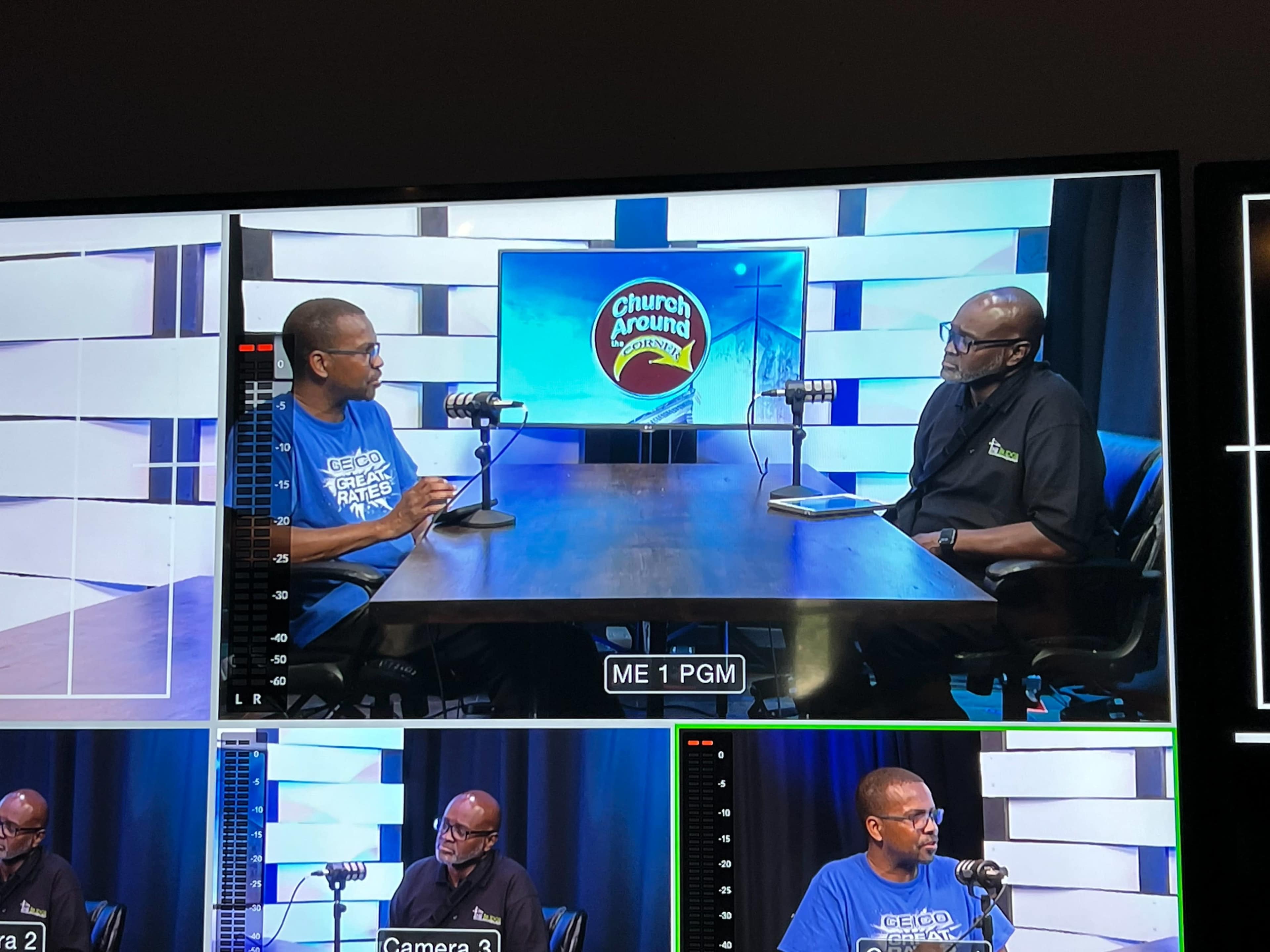 Two men are seated at a table in a studio setting, discussing topics related to the "Church Around" program, with microphones positioned in front of each.