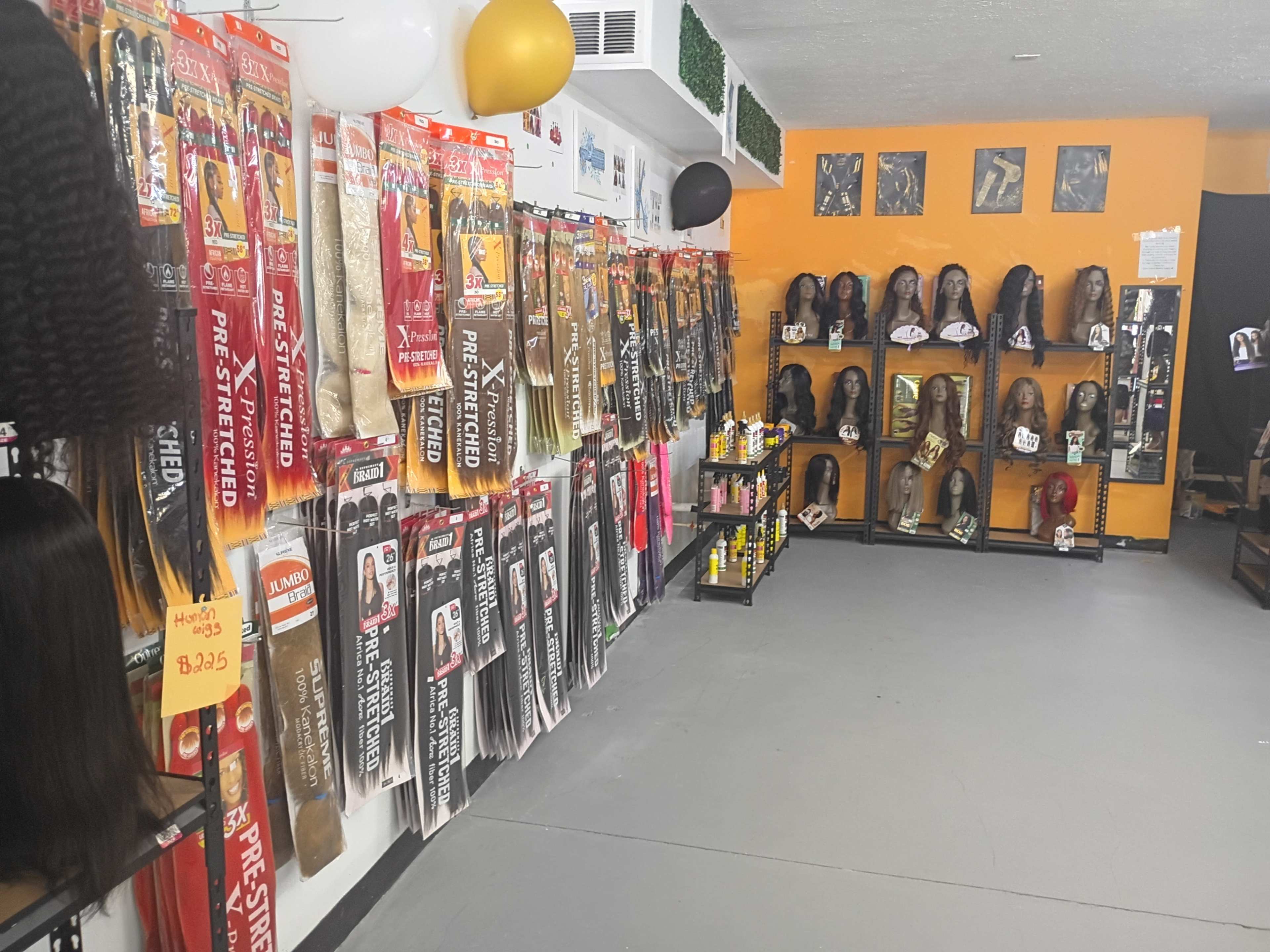 The image shows a store interior featuring shelves lined with various types of hair extensions and wigs.
