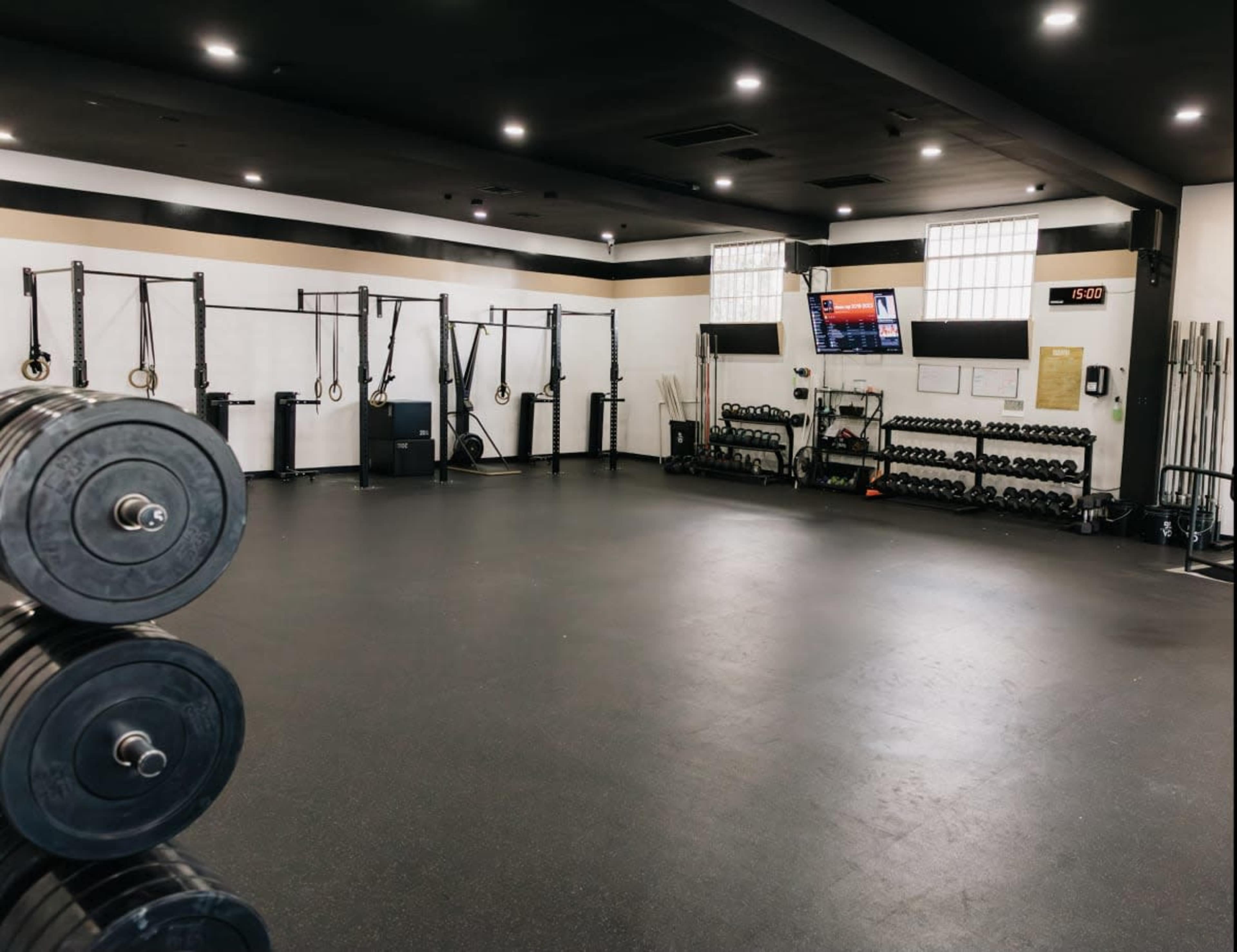 A spacious gym with workout equipment including dumbbells, weight plates, and resistance training apparatus along the walls.