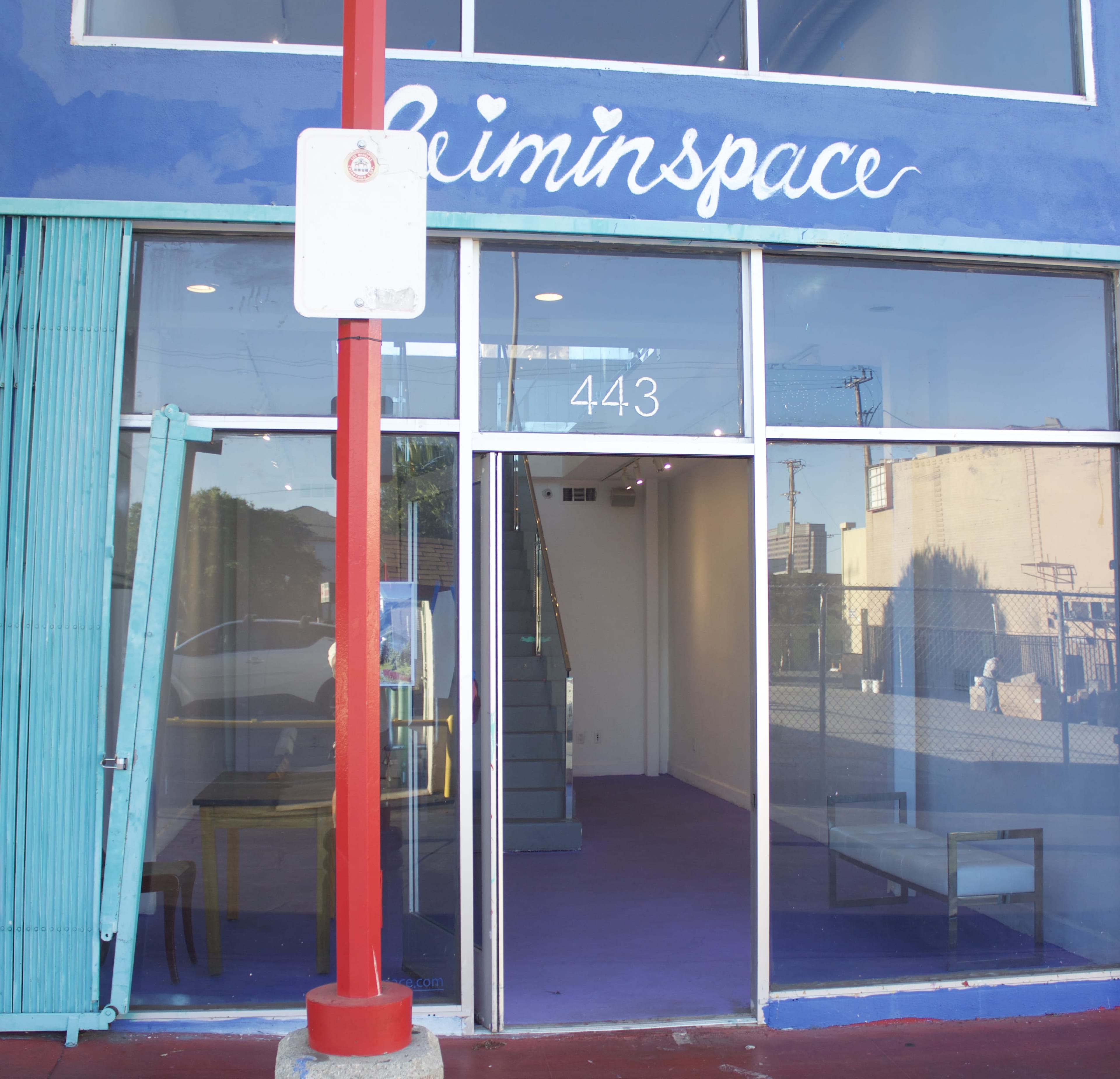 The image shows the exterior of a storefront with the name "leminspace" painted above the entrance, featuring large glass windows and a purple floor visible inside.