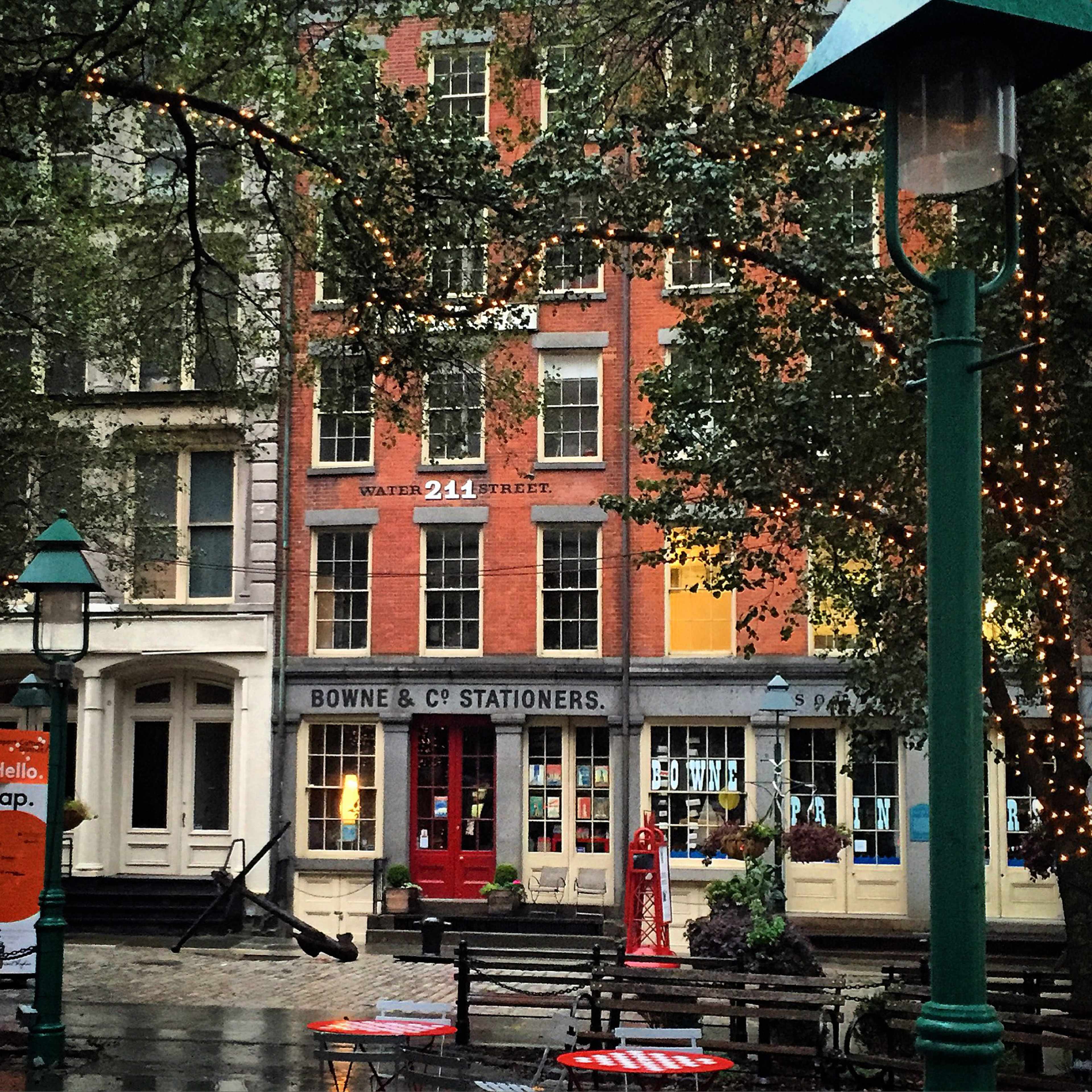 The image shows a brick building at 241 Water Street with the signage "BOWNE & Co. Stationers" on the ground floor, surrounded by trees and streetlights.