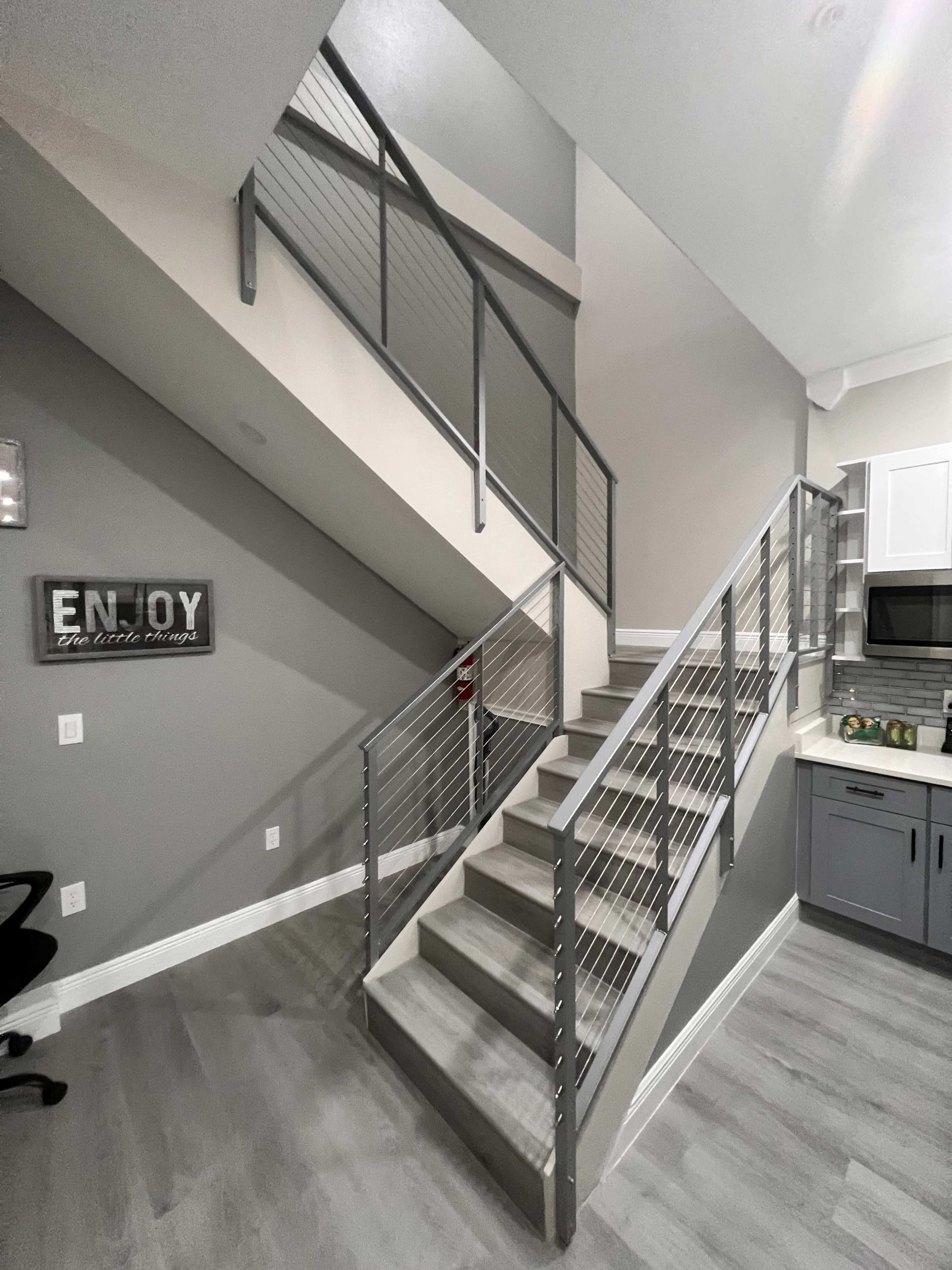 A modern staircase with metal railings leading to an upper level in a well-lit interior space.