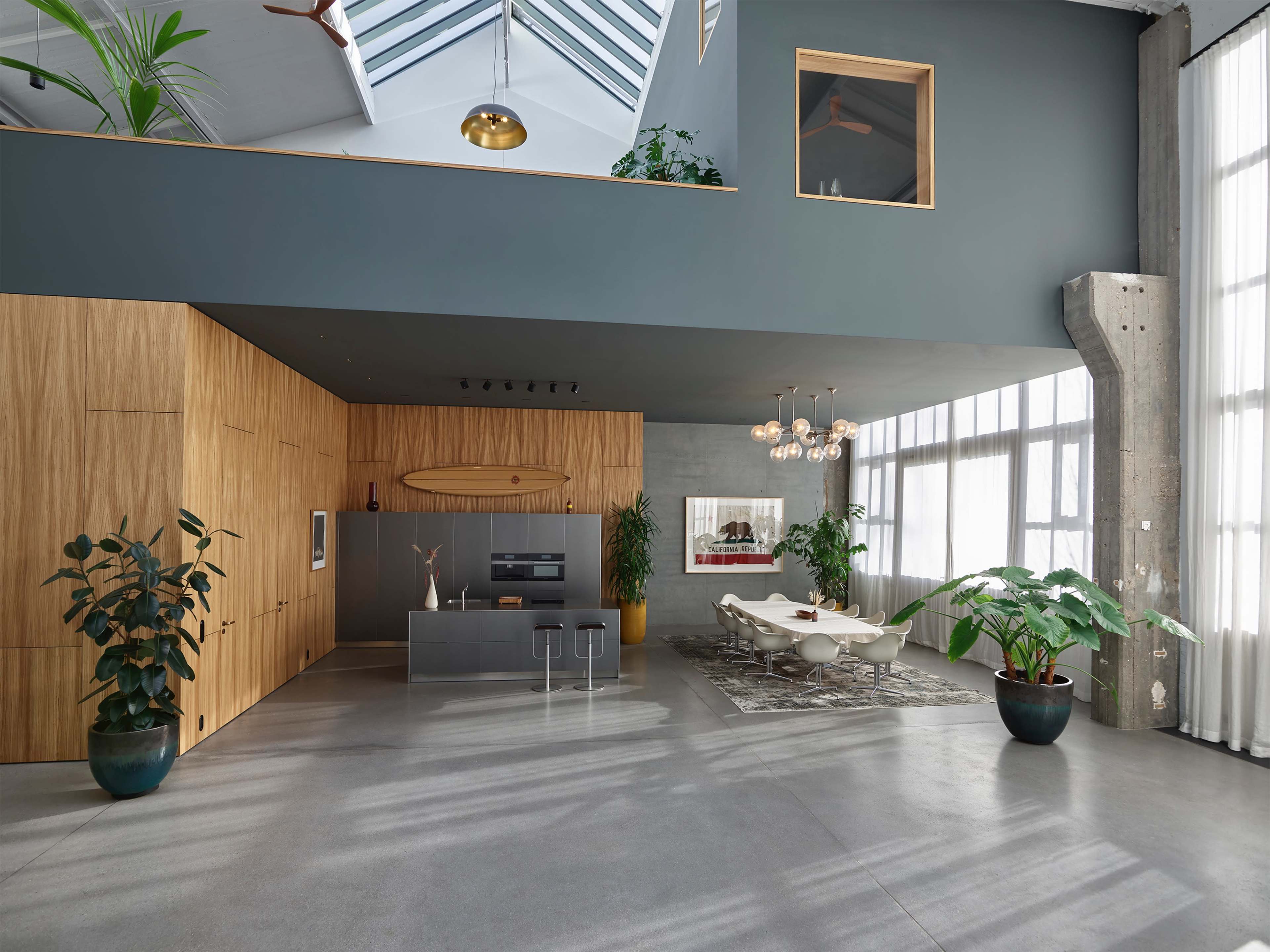 A modern, open-concept living area with a kitchen island, large windows, and indoor plants.