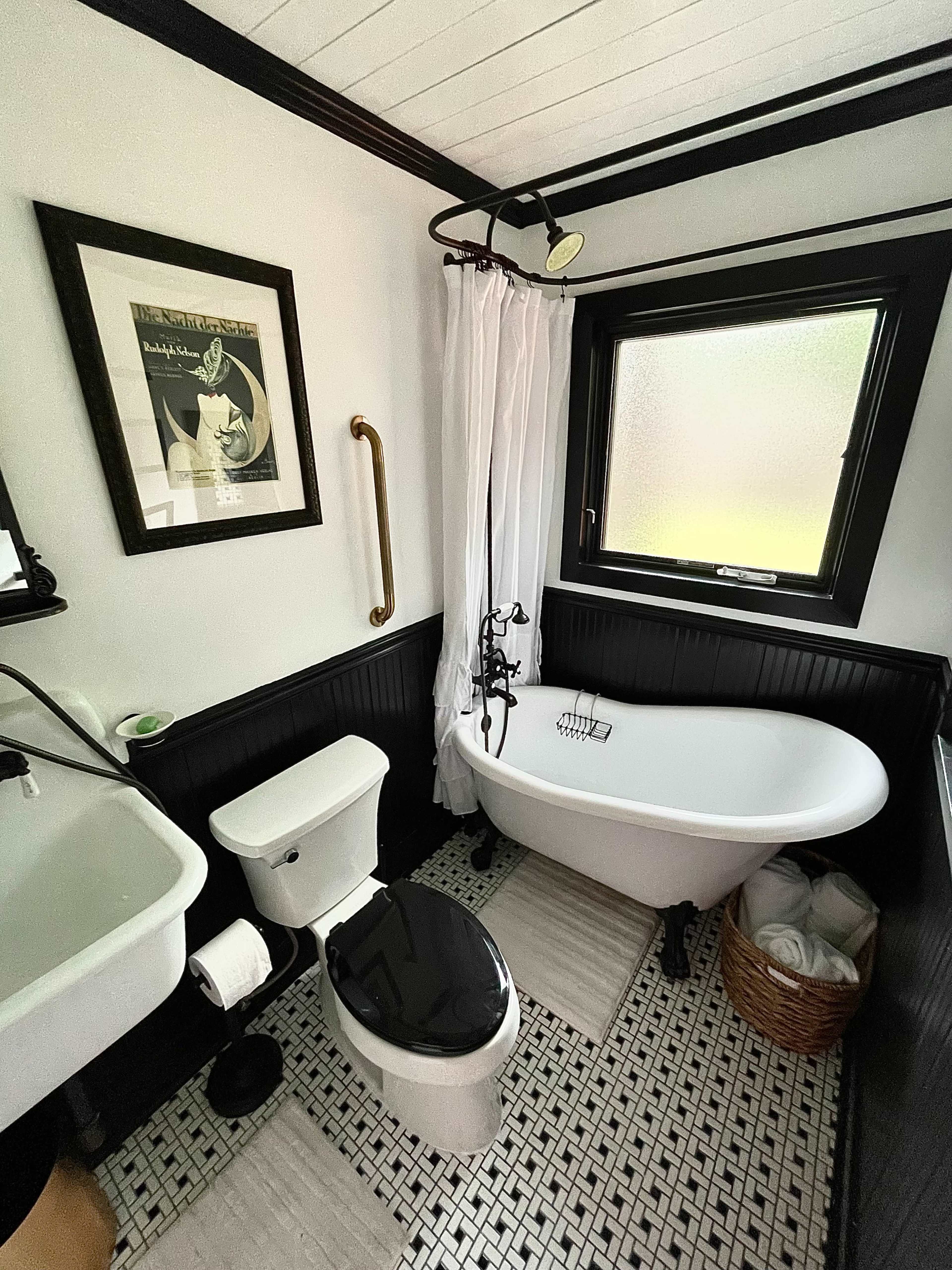 The image shows a modern bathroom featuring a freestanding tub, a toilet, a sink, and tiled flooring.