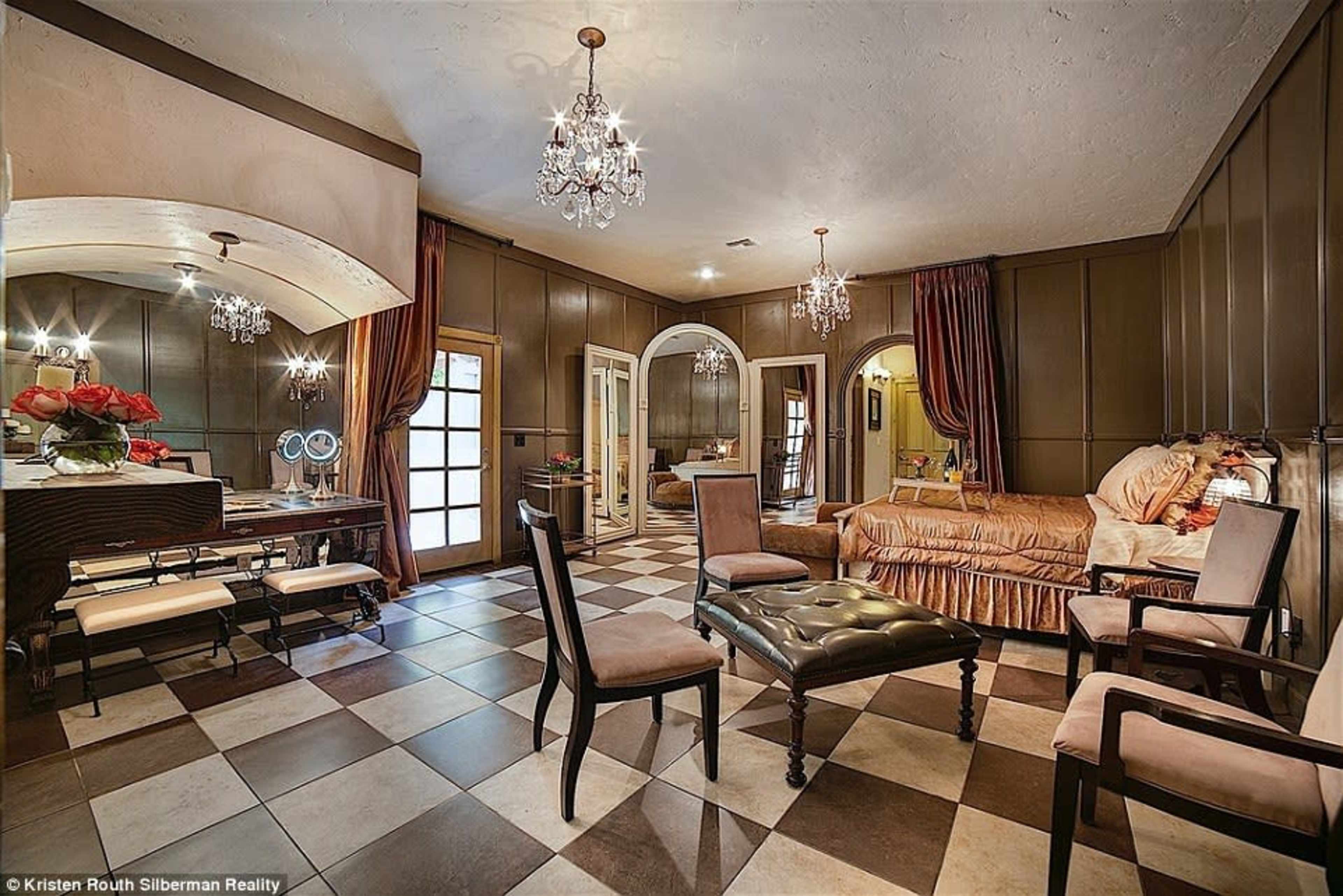 The room features a checkered floor, a seating area with upholstered chairs, a sofa, and decorative chandeliers.