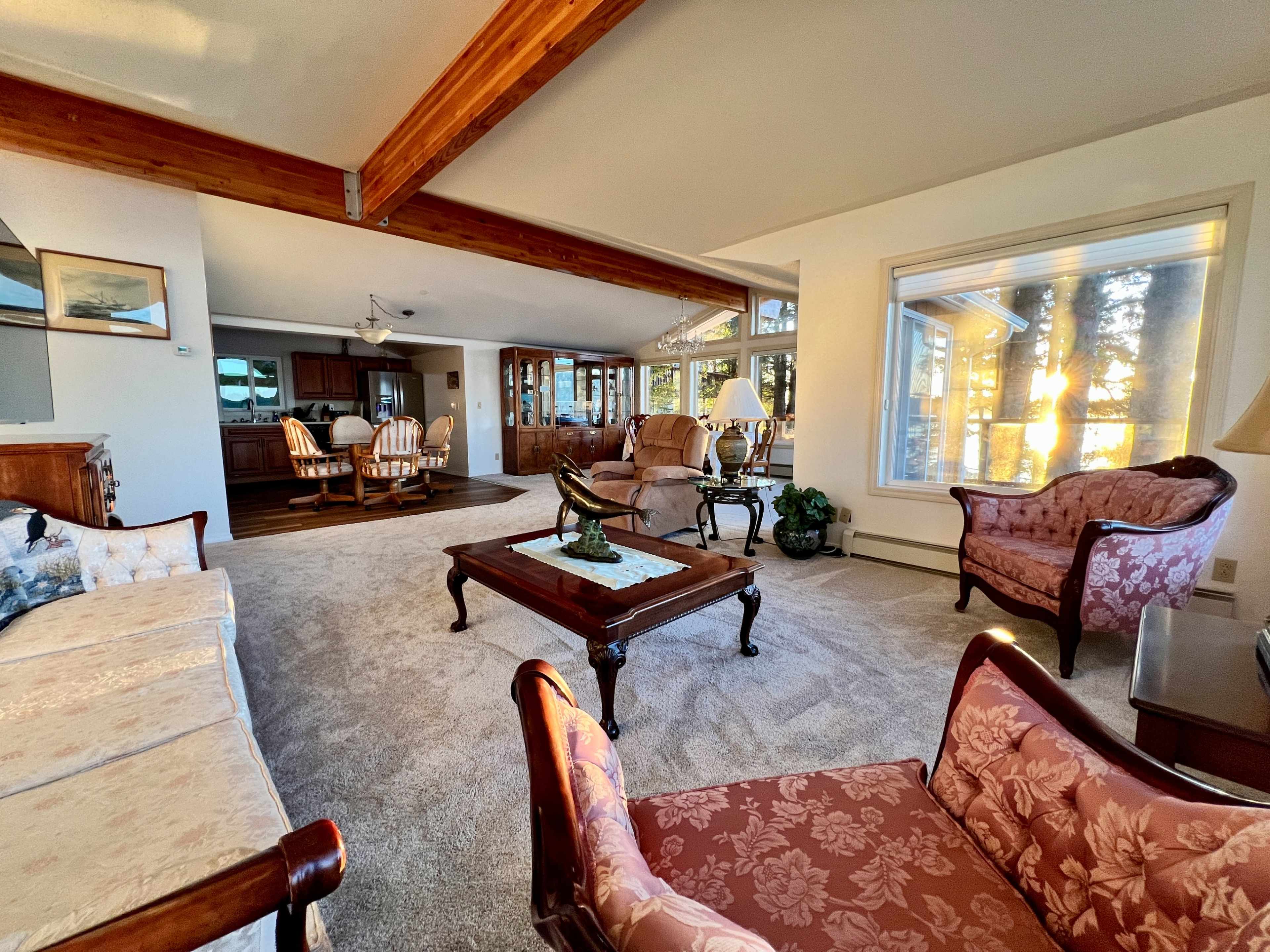 The spacious living room features a combination of comfortable seating, large windows providing natural light, and a view of the outdoors.