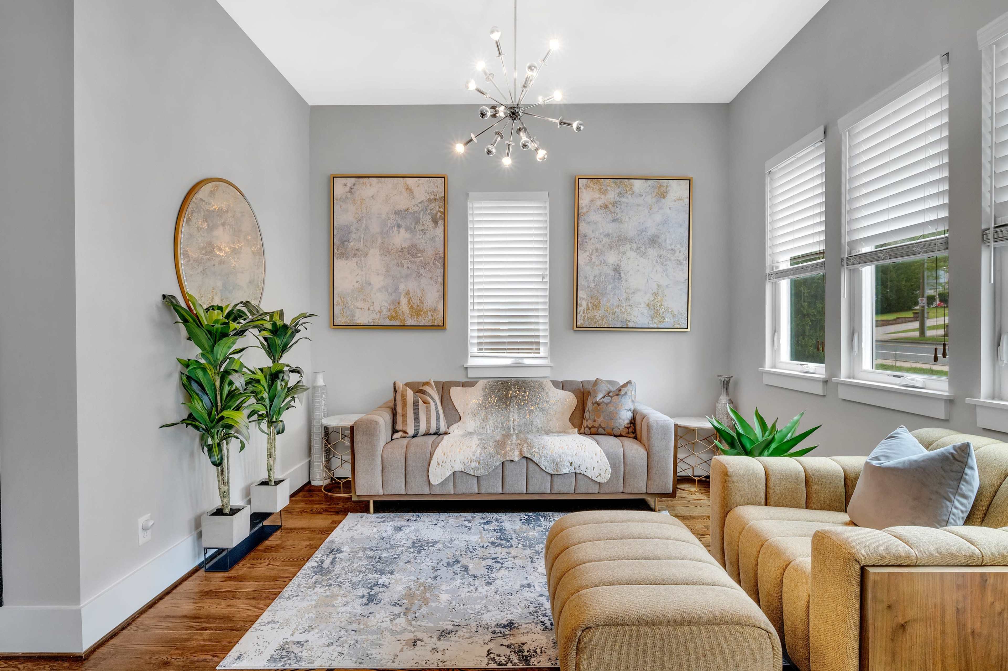 The living room features a modern design with a gray color scheme, a sofa with decorative pillows, a paired armchair, and two large paintings on the walls.