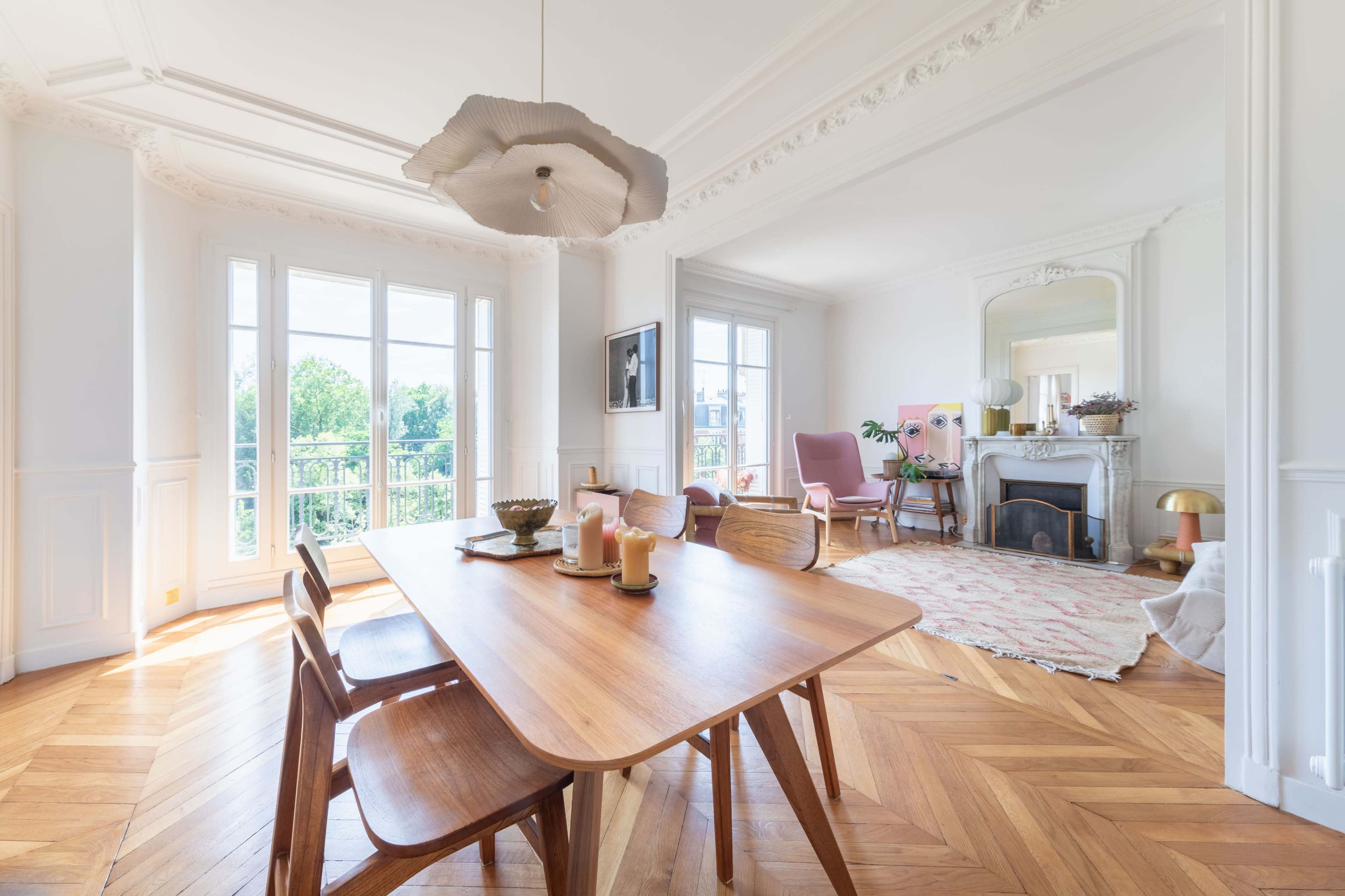 A spacious dining area with a wooden table, surrounded by elegant chairs, and large windows allowing natural light to fill the room, featuring a cozy seating area and decorative accents.