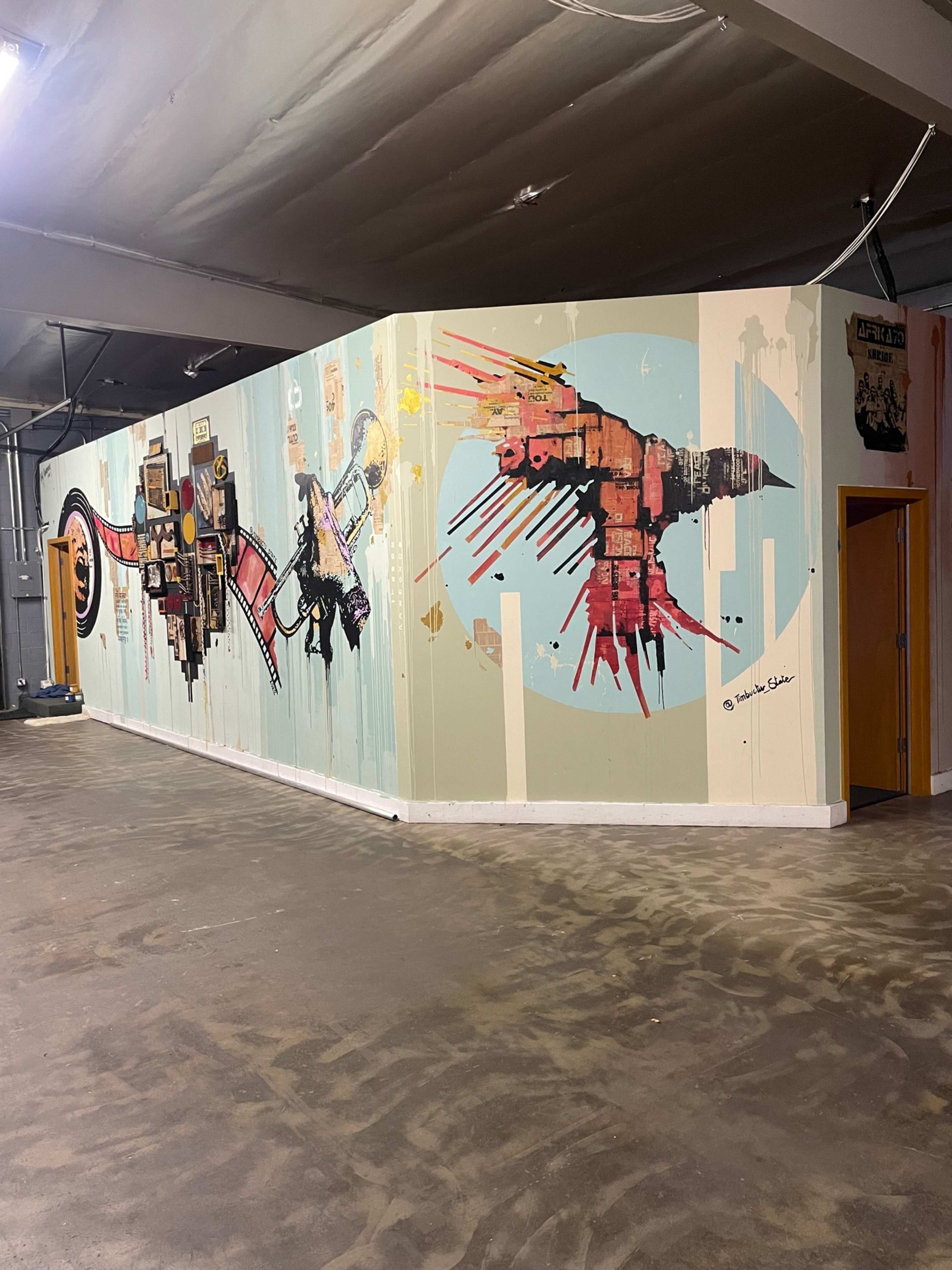 A vibrant mural covering a wall in a spacious indoor area, featuring abstract shapes and colorful designs.