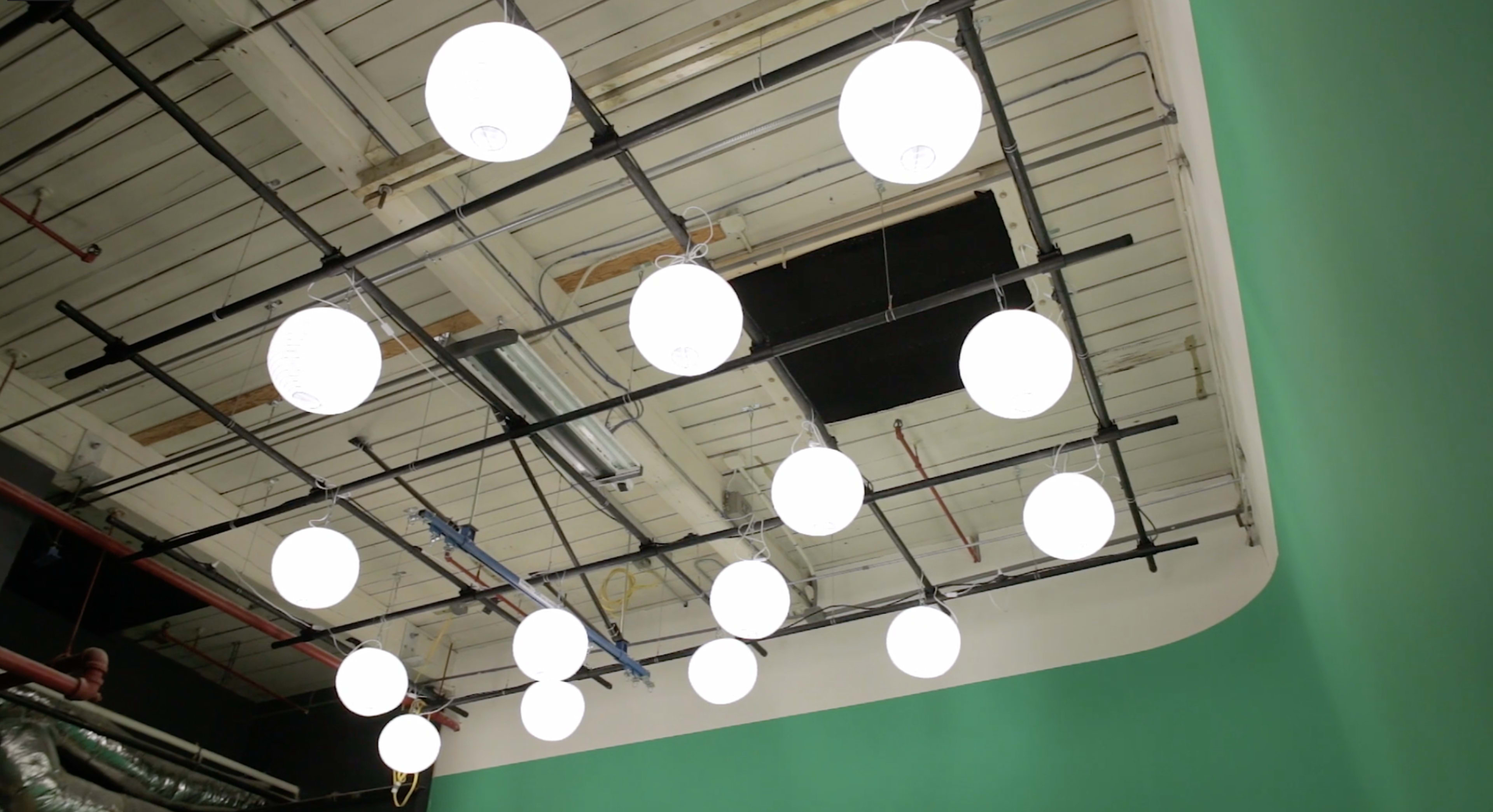 A ceiling with circular white lights suspended above a green wall.