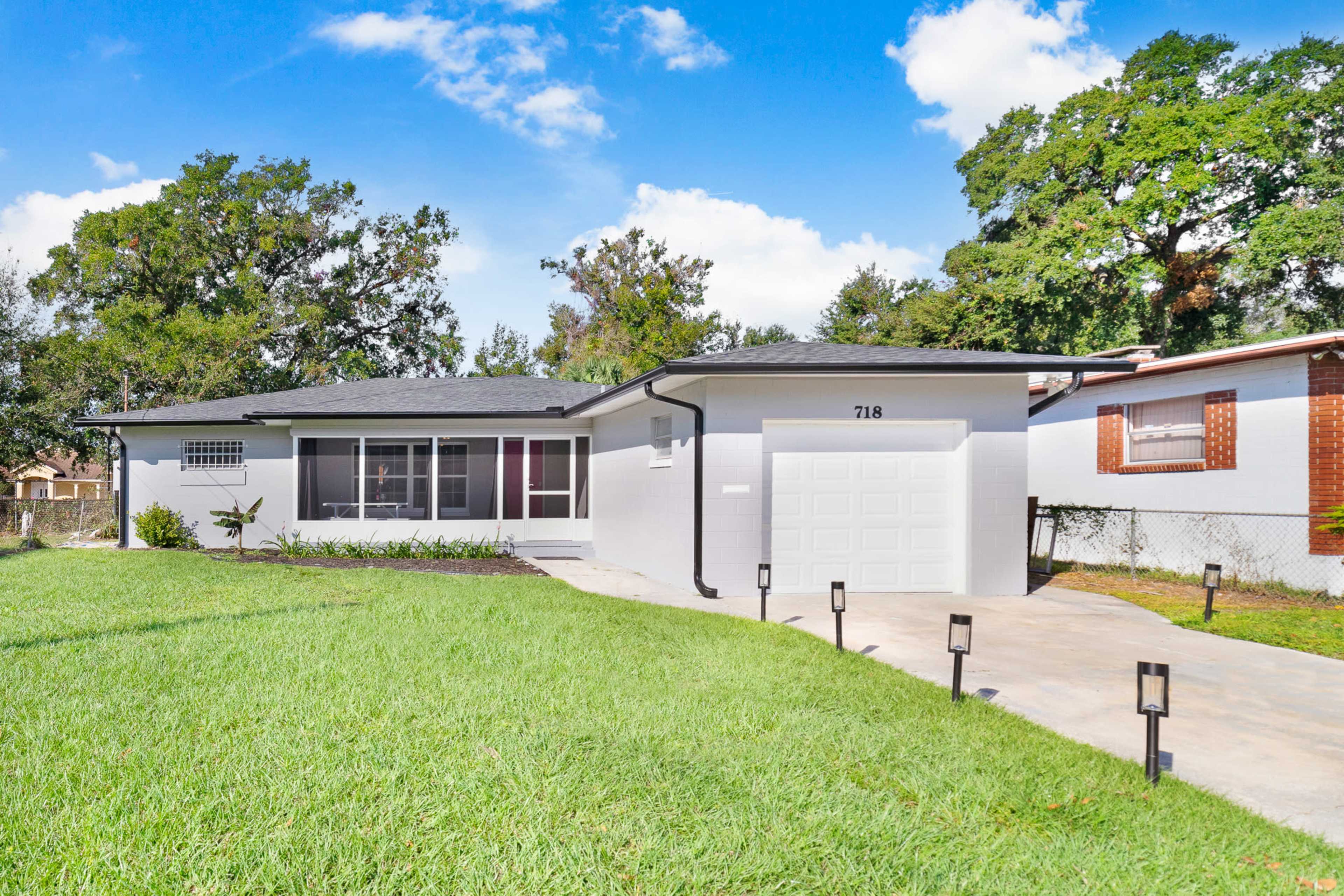 A single-story house with a light-colored exterior, a front lawn, and a driveway leading to a garage.