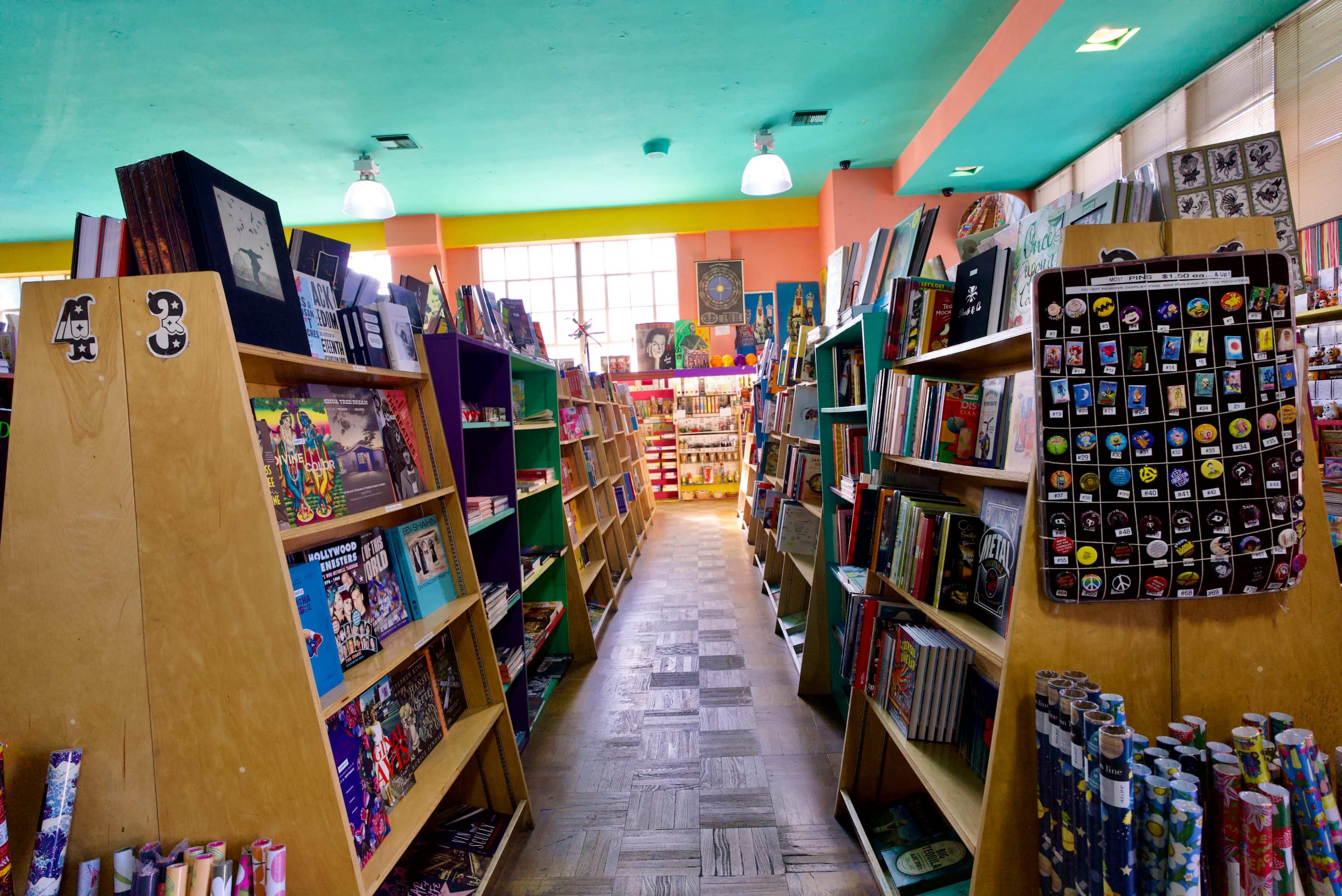 The image shows a colorful bookstore interior with wooden bookshelves filled with various books and decorative items, illuminated by overhead lights.