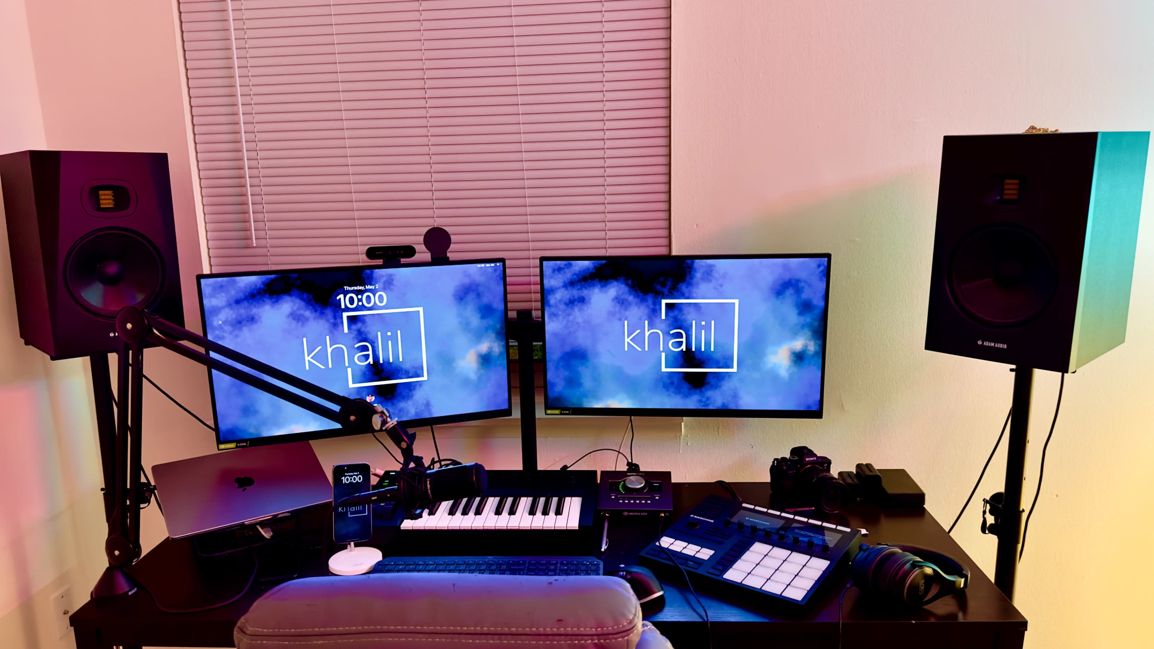 A workspace with two monitors displaying the name "khalil," a keyboard, audio equipment, and a camera, all arranged on a desk.