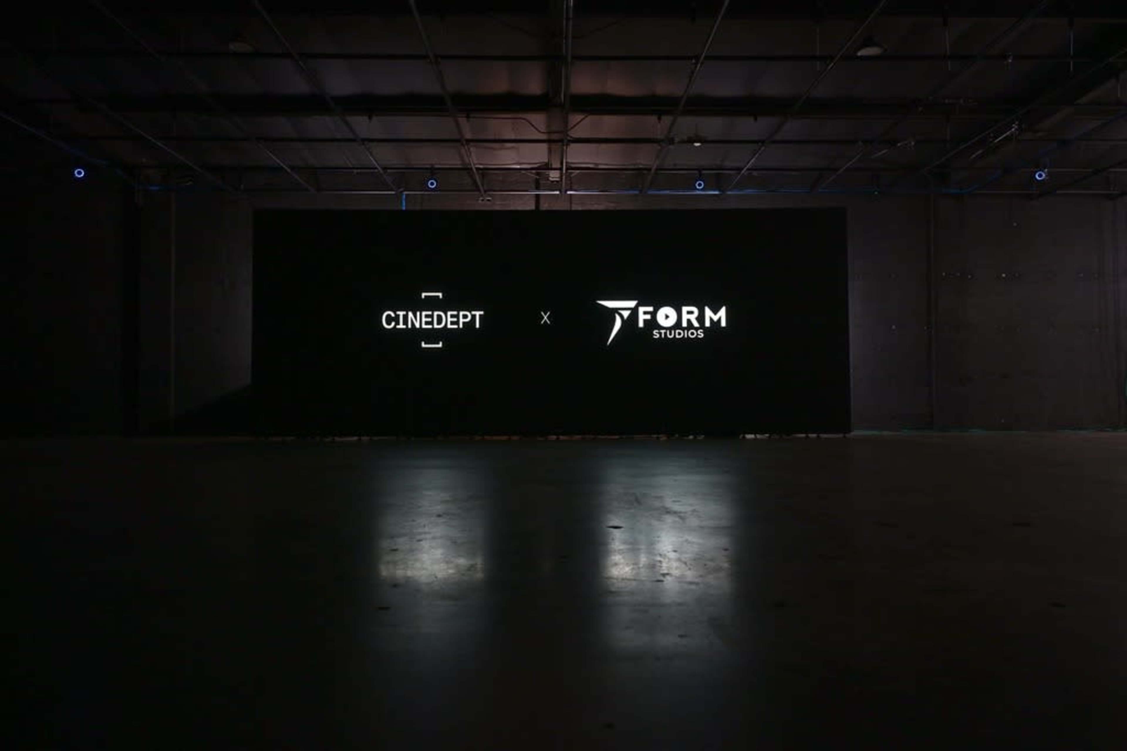 The image shows a dimly lit space with a black wall displaying the logos of "Cinedept" and "Form Studios."