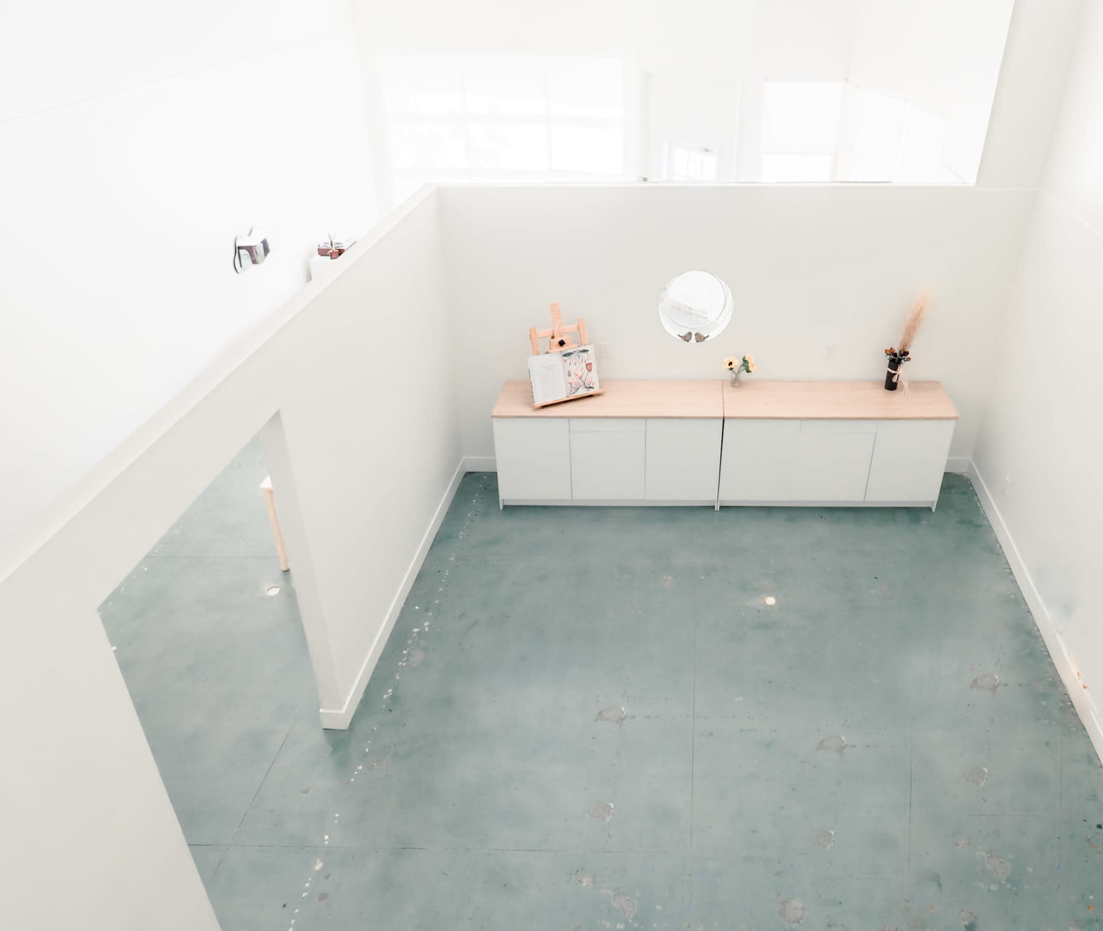 A spacious, minimalistic room with a light-colored concrete floor and a long, simple wooden countertop along one wall.