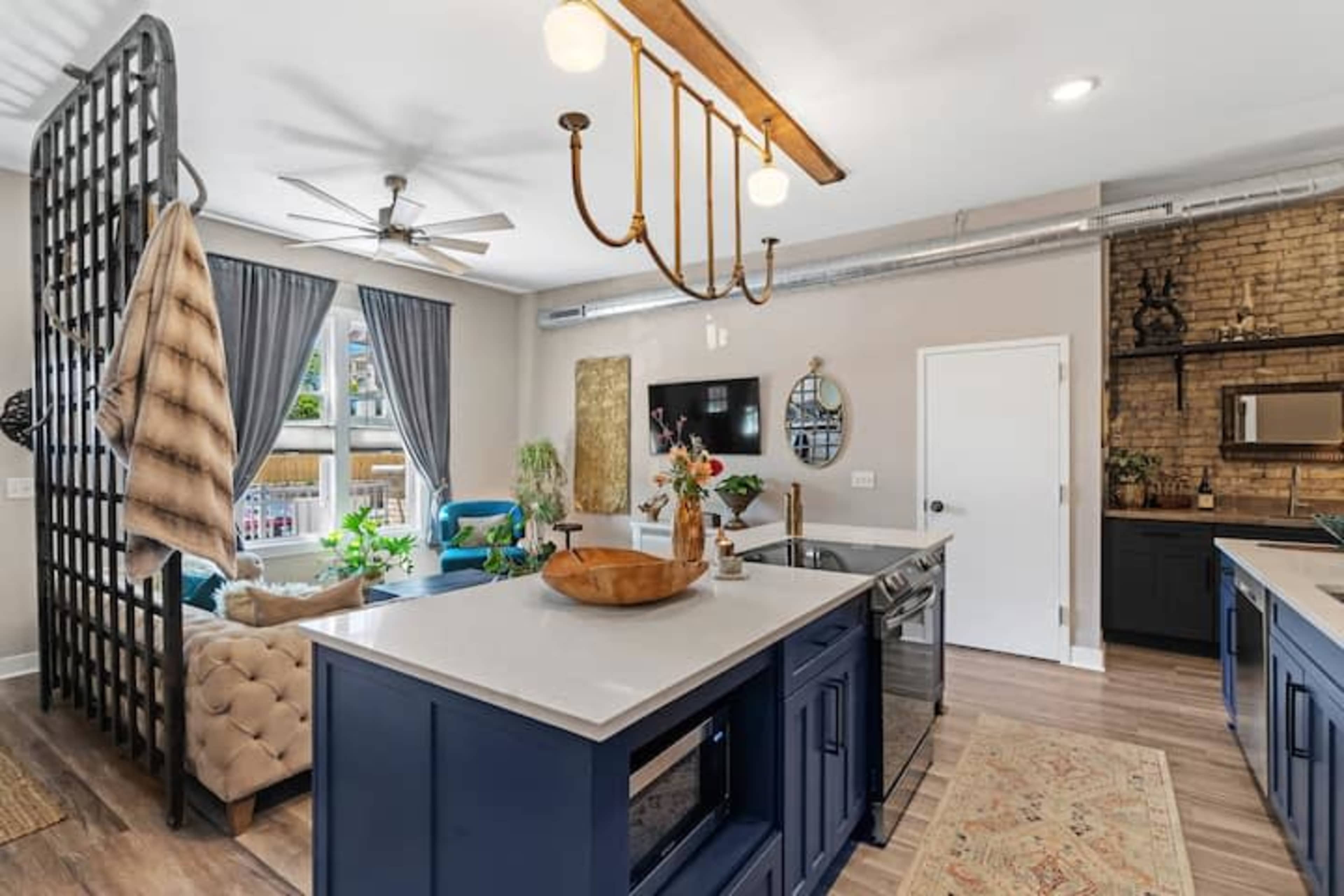 A modern kitchen and living area with navy blue cabinetry, a large island, and a cozy seating arrangement separated by a decorative screen.