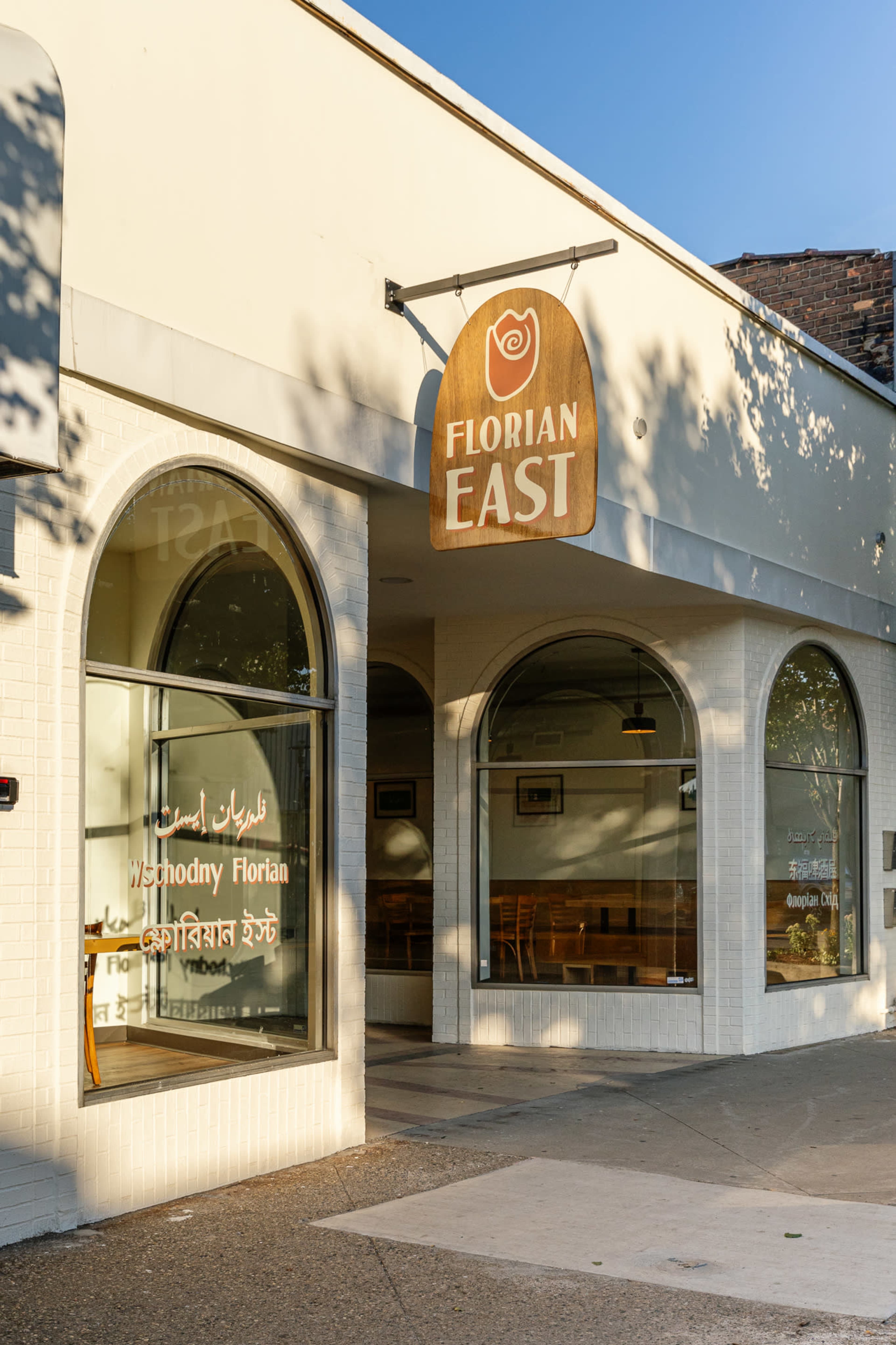 The image shows the exterior of a restaurant named "Florian East," featuring a wooden sign and large arched windows.