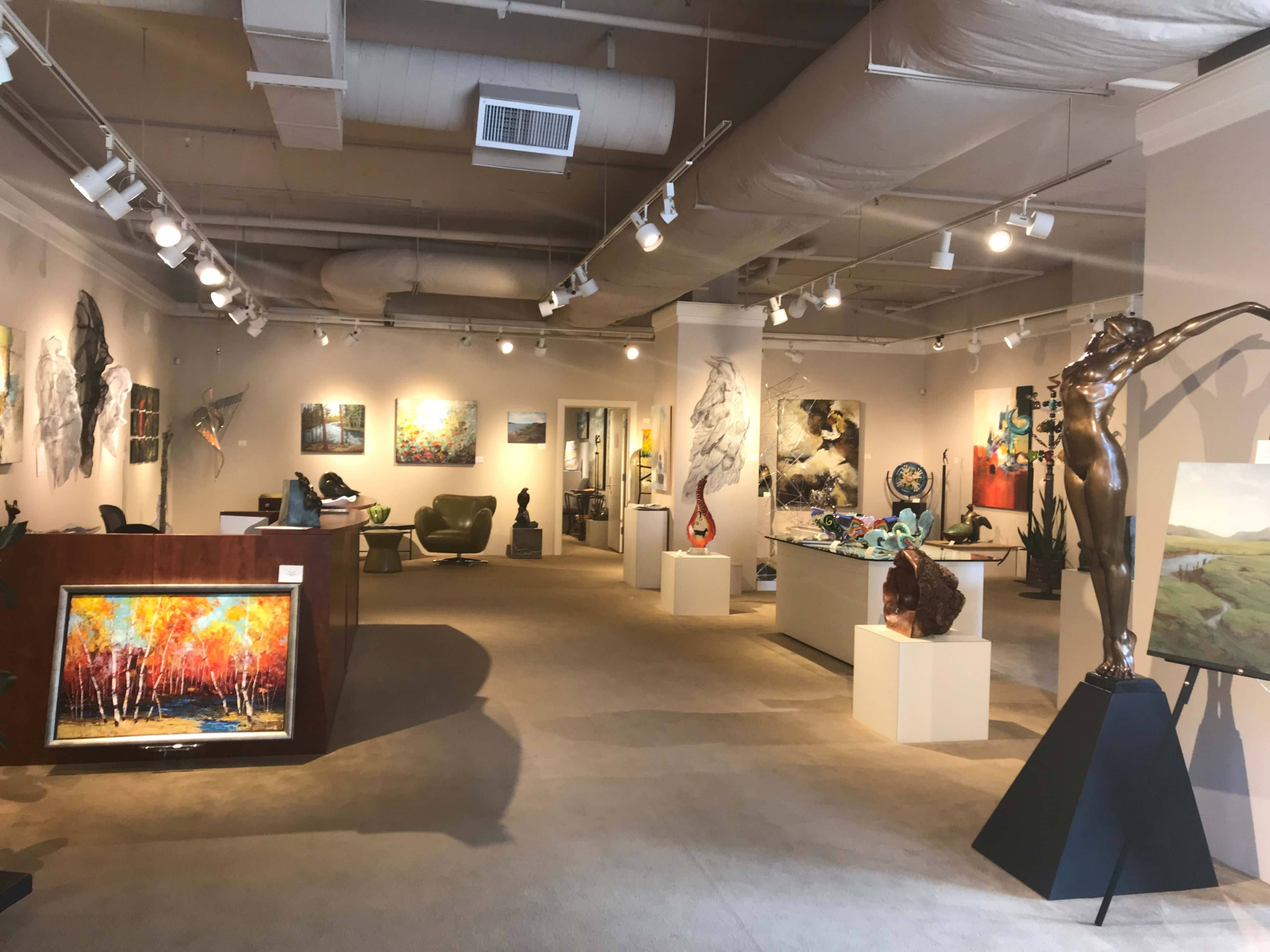 An art gallery featuring a variety of paintings and sculptures displayed throughout the spacious room.