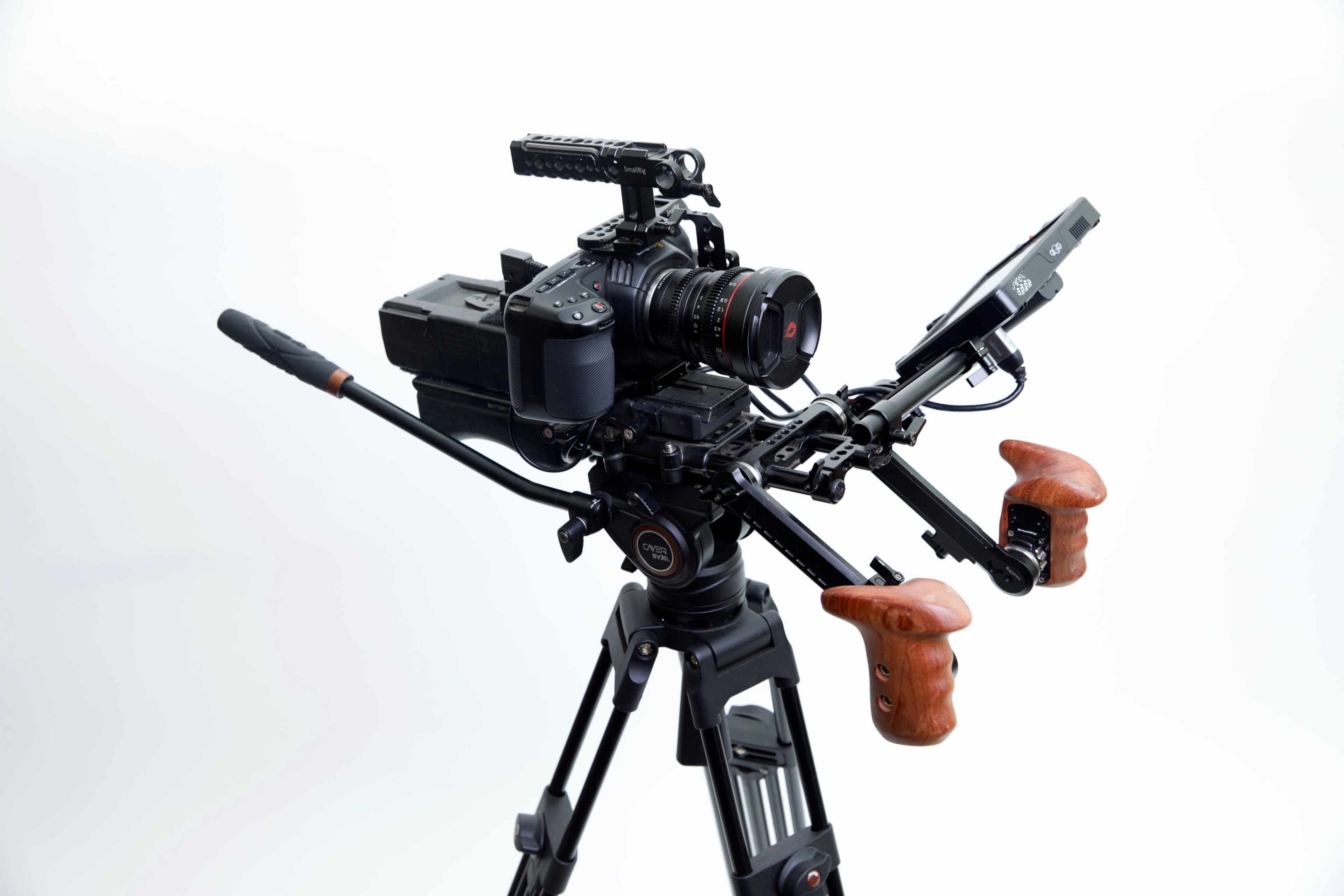 A professional camera setup is mounted on a tripod, featuring a lens, a rig, and wooden grips.