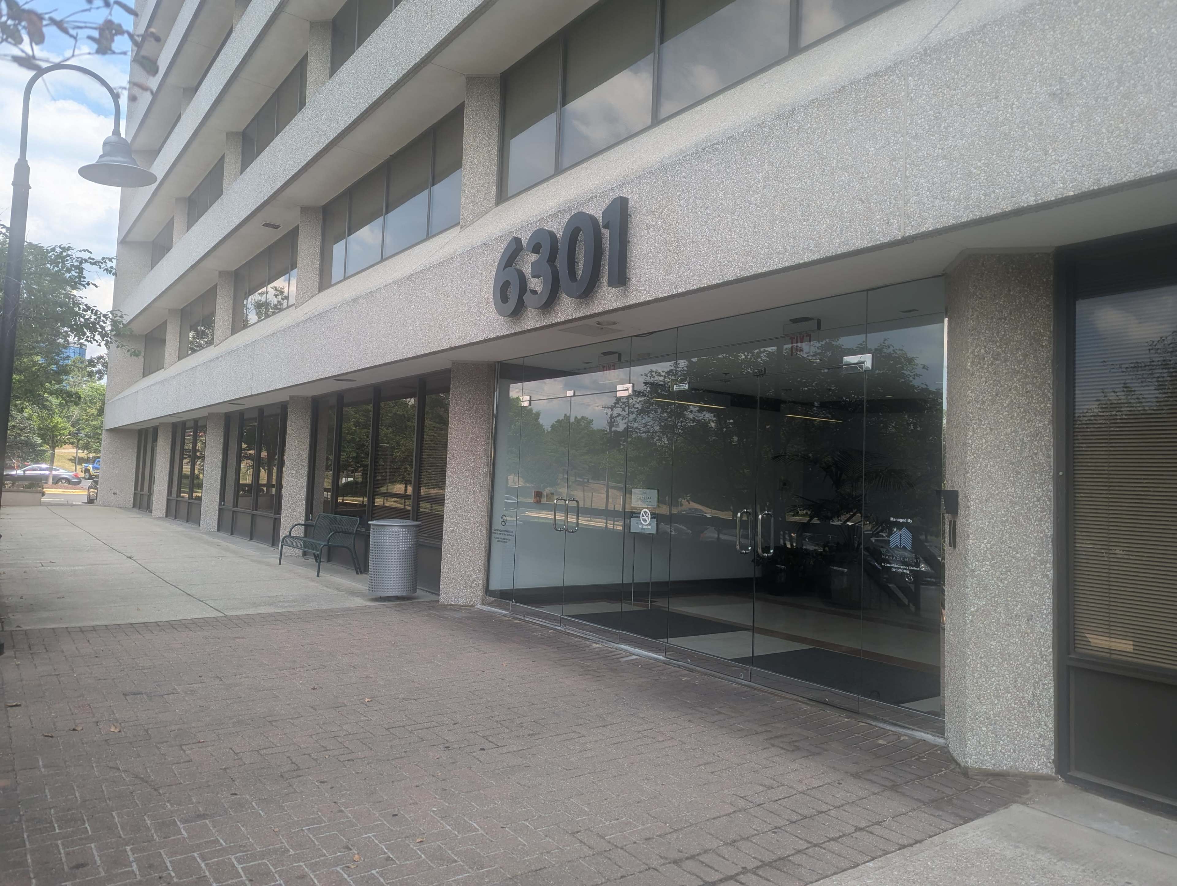 The image shows the entrance of a building at 6301, featuring large glass doors and a concrete facade.